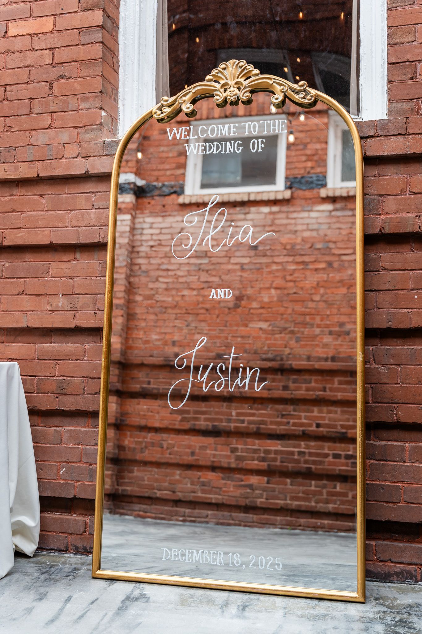 Gold ornate mirror wedding welcome sign for Ikia and Justin, December 18, 2025.