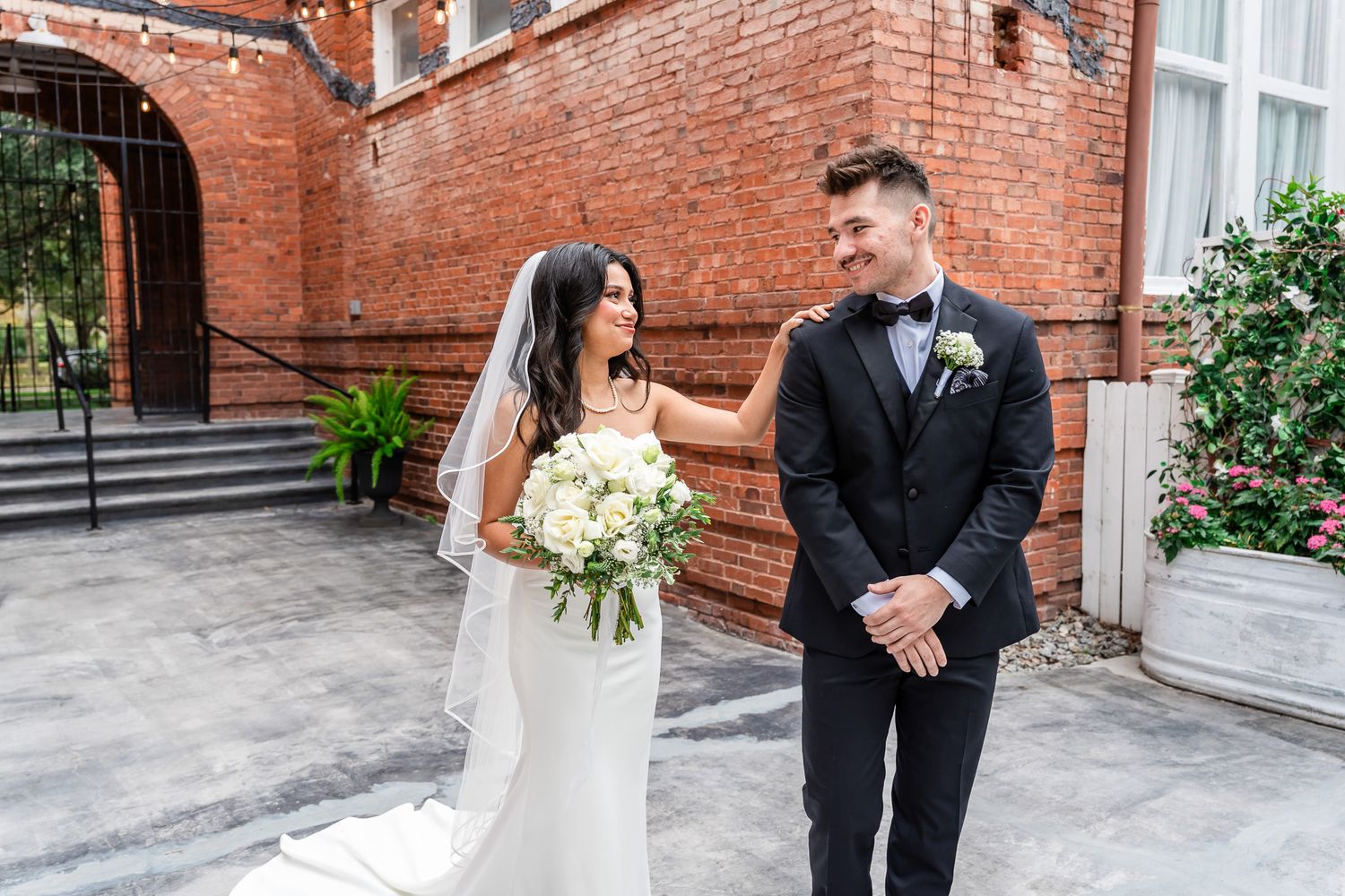 Bride and groom sharing first look moment outside brick building wedding venue.