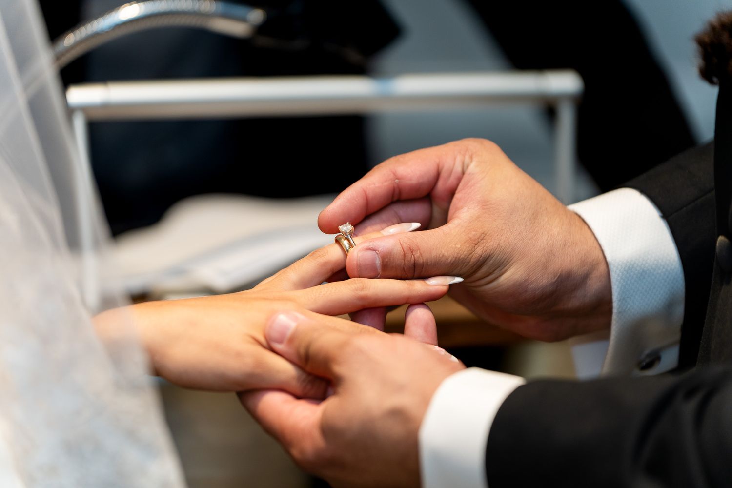 Close-up of groom placing wedding ring on brides finger during the ring exchange ceremony.