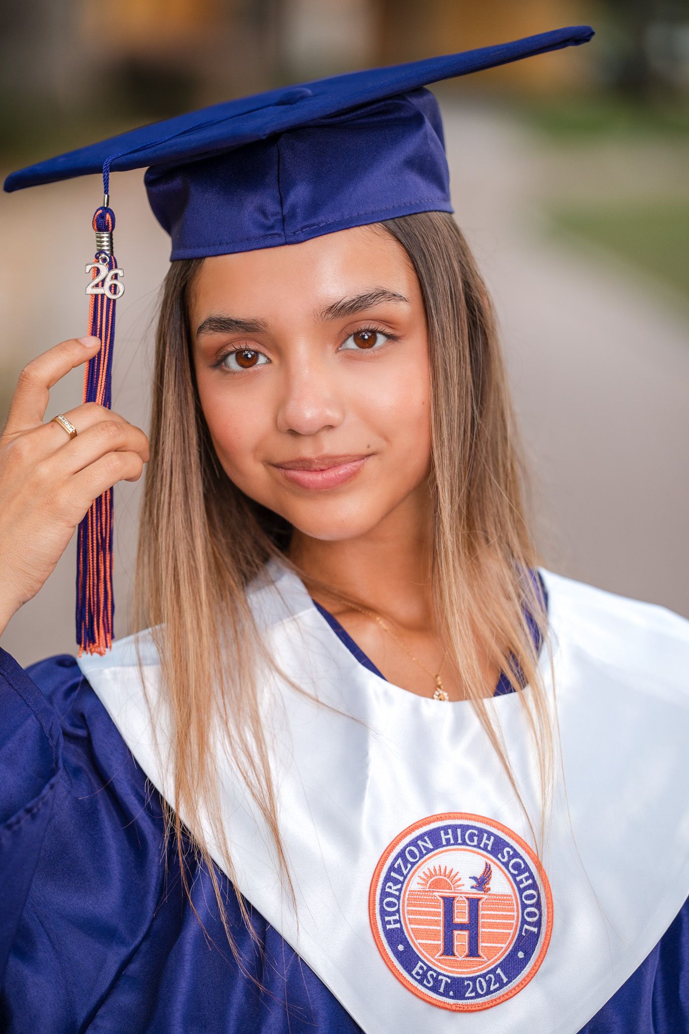 Close-up portrait of Horizon High School graduate in blue cap and gown holding tassel.