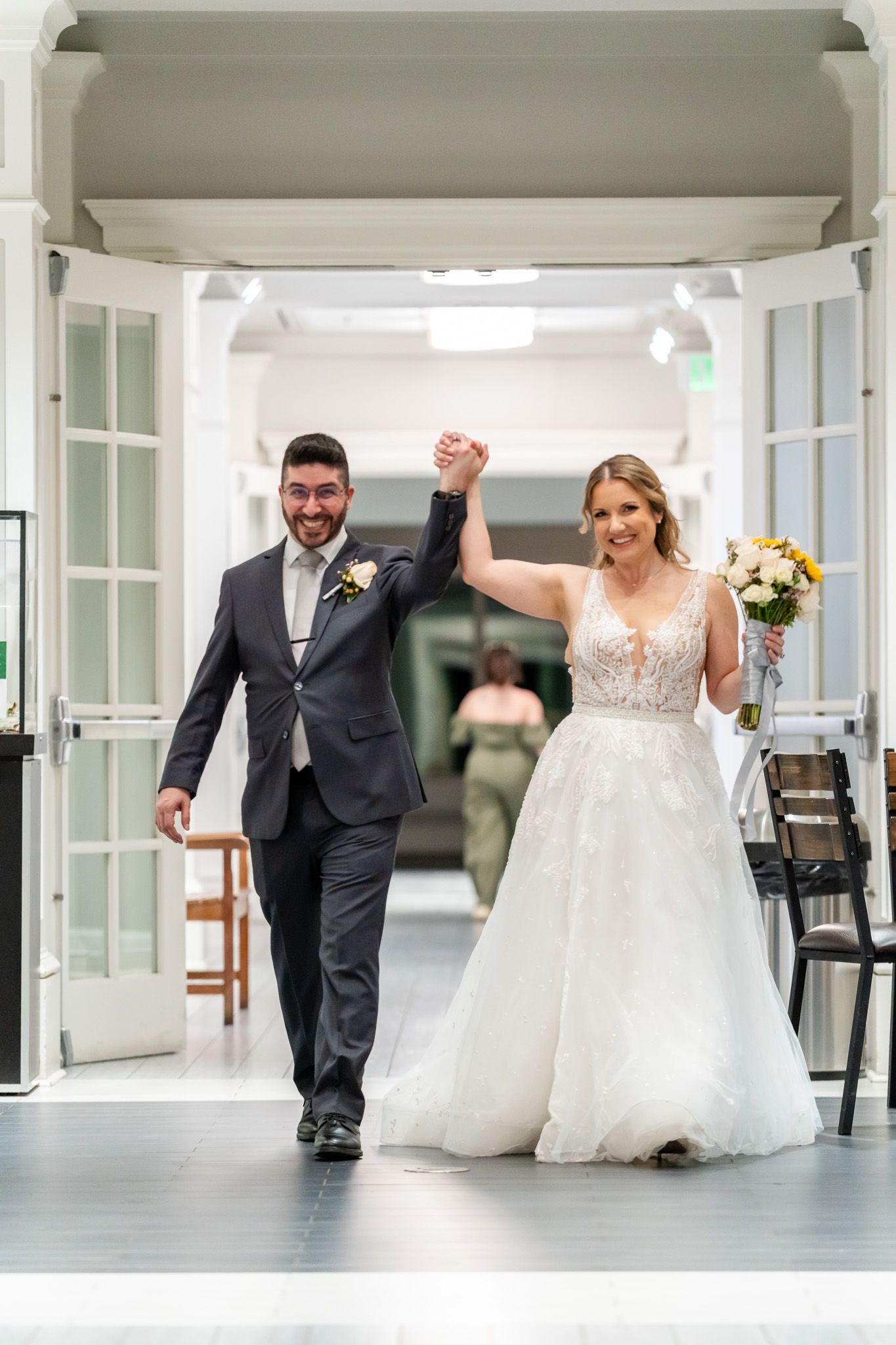 Newlyweds make grand entrance holding hands raised in celebration at wedding reception.