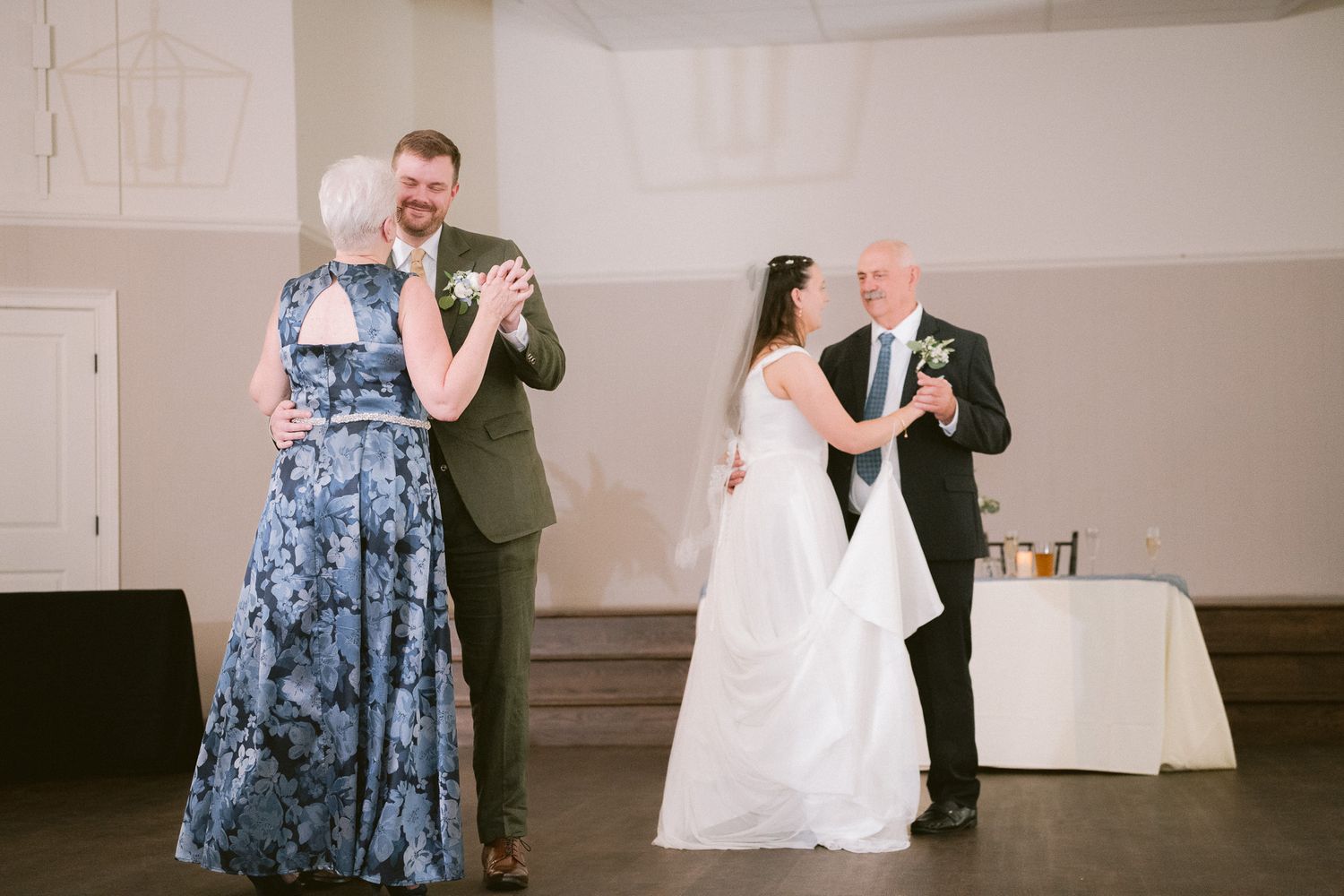 Bride and groom share parent dances with their mothers at elegant wedding reception.