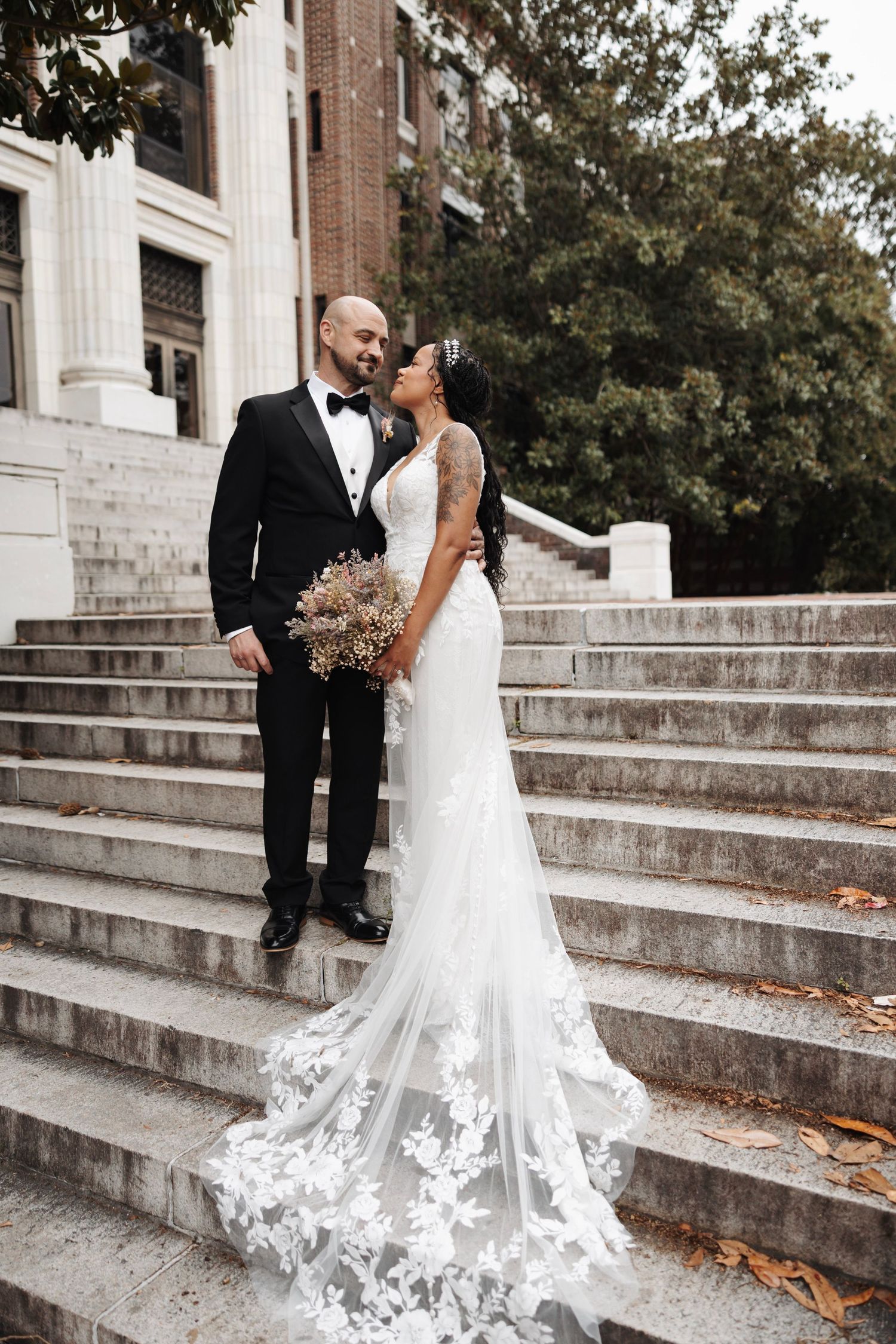 Bride and groom sharing romantic moment on stone steps of historic building.