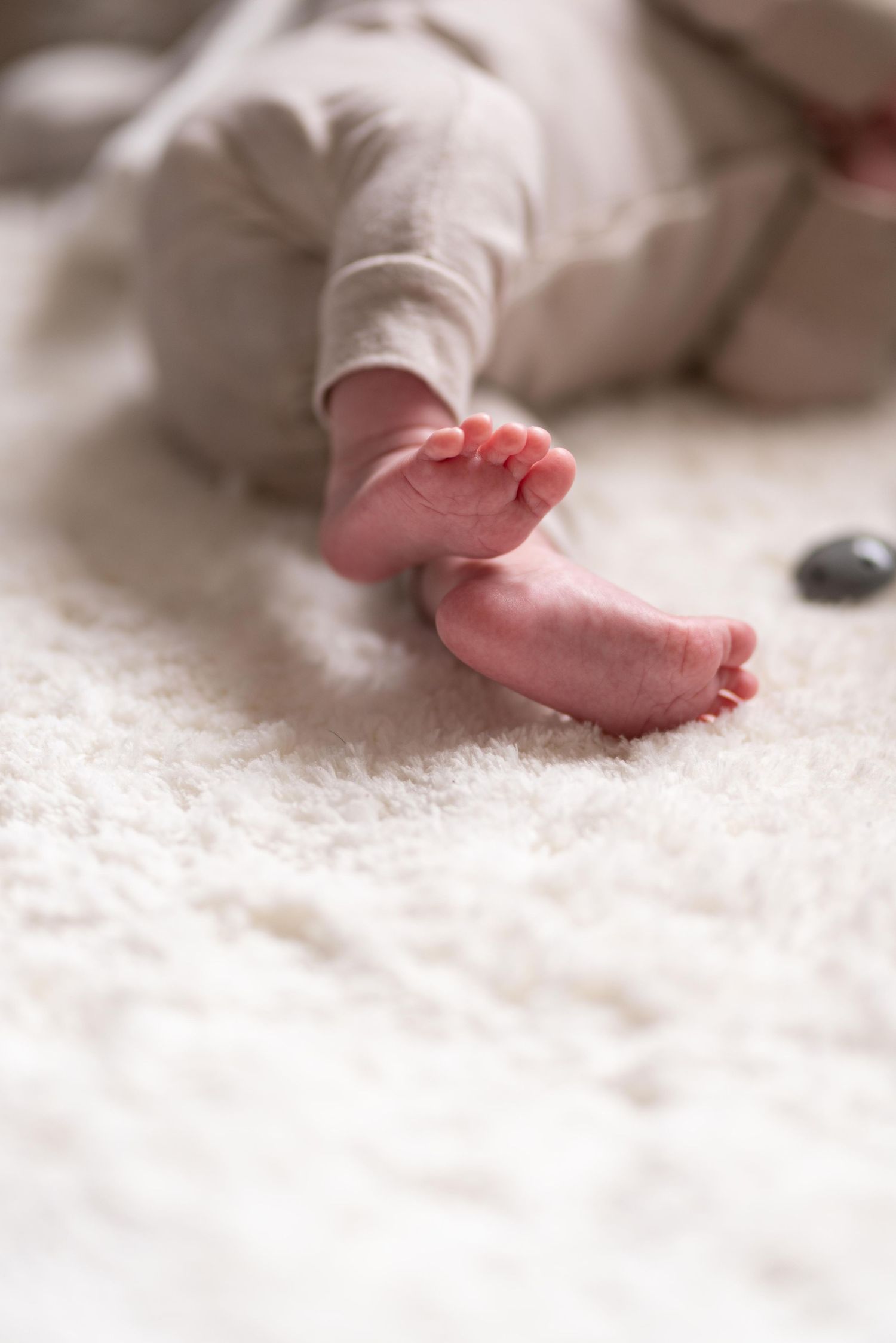 Gros plan sur les petits pieds d'un nouveau-né posés sur une douce couverture blanche et moelleuse, sur fond flou.