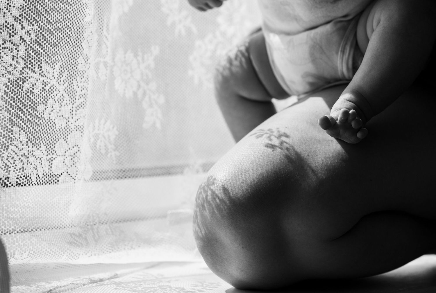 Close up of The Mother's Eye photographer holding her baby next to the window. Motherhood photography East Dulwich, South East London.
