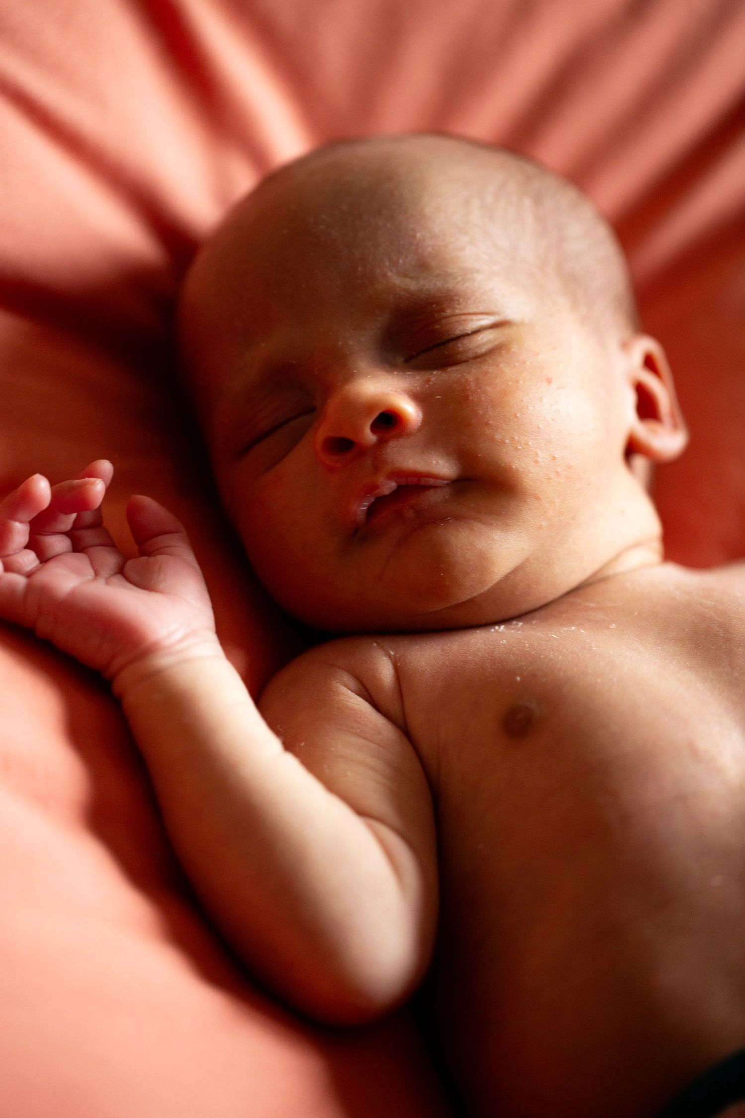 Newborn happily sleeping on a bed. Newborn, Postpartum and Fourth Trimester photography by The Mother's Eye, Norwood, South East London.