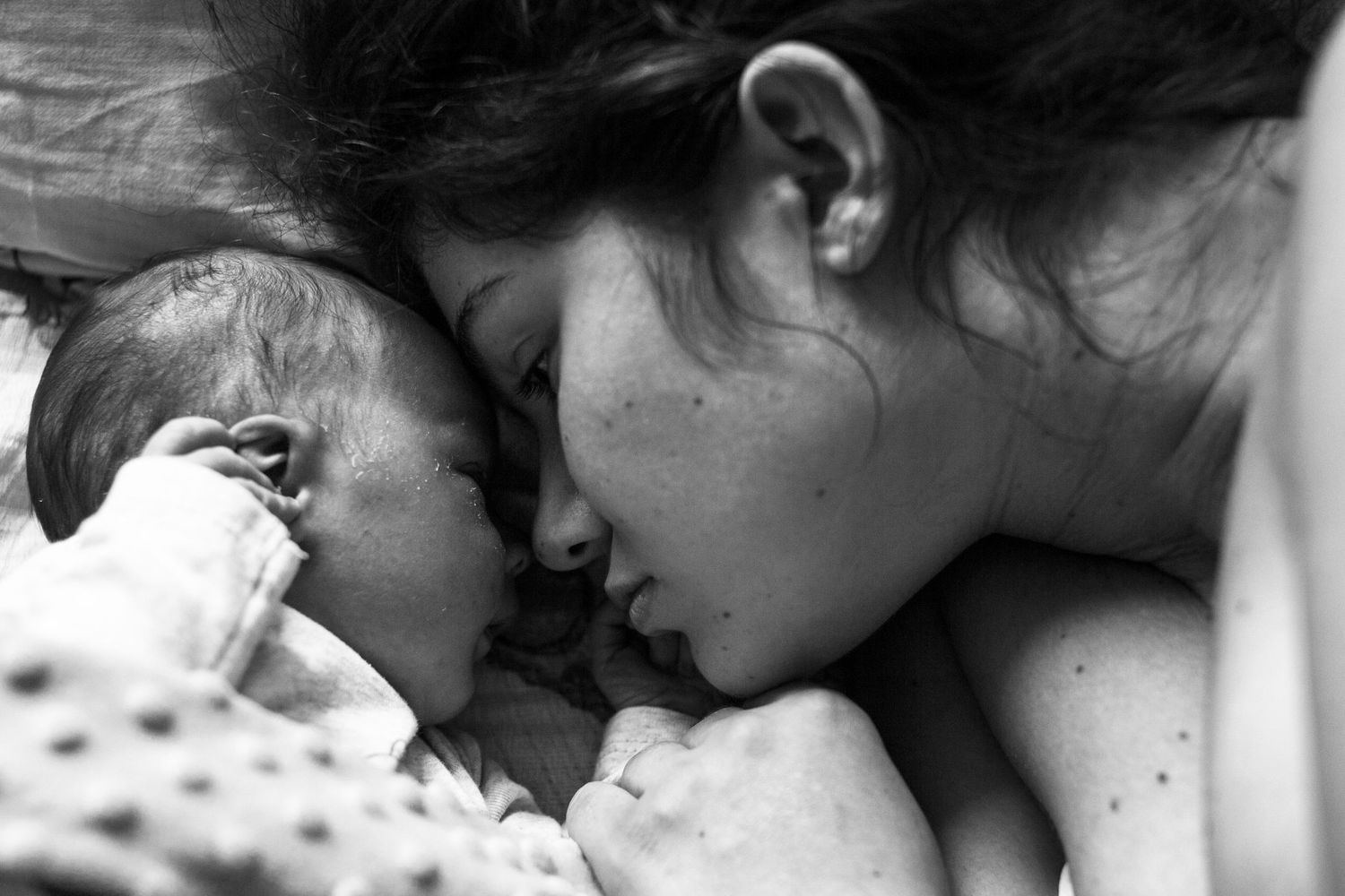 Close-up of a mum laying down face to face with her newborn. Motherhood, newborn and birth photography East Dulwich, South East London.