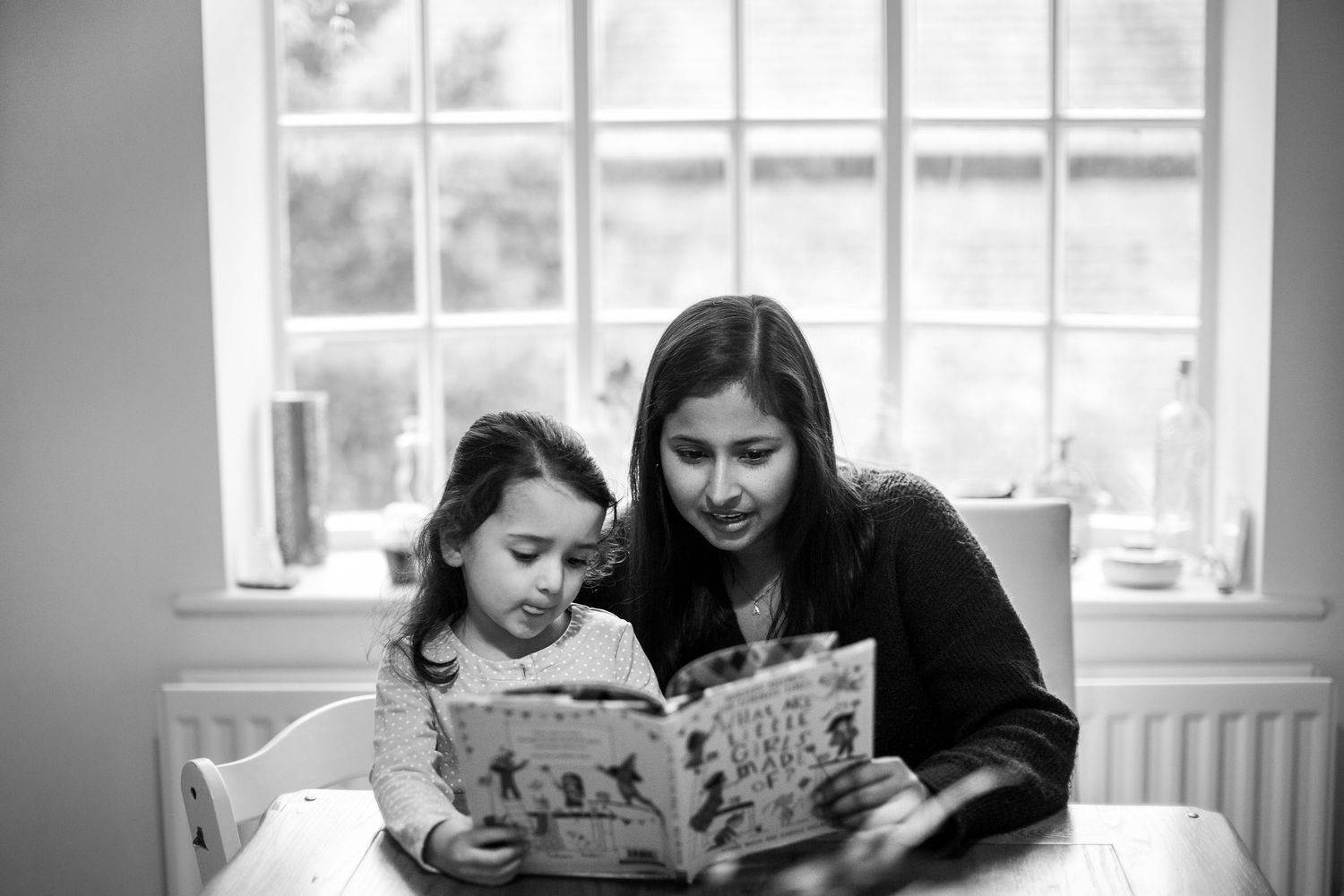 A mother and daughter reading a book at a table. Motherhood and childhood photo sessions by The Mother's Eye in Deptford, South East London.
