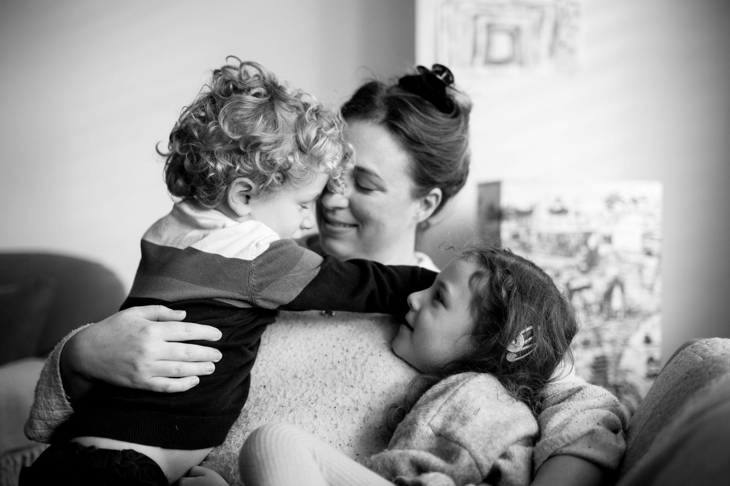 Mum cuddles her 2 kids in a photo session. The Mother's Eye - candid, poetic documentary-stele motherhood photography in Peckham, London.