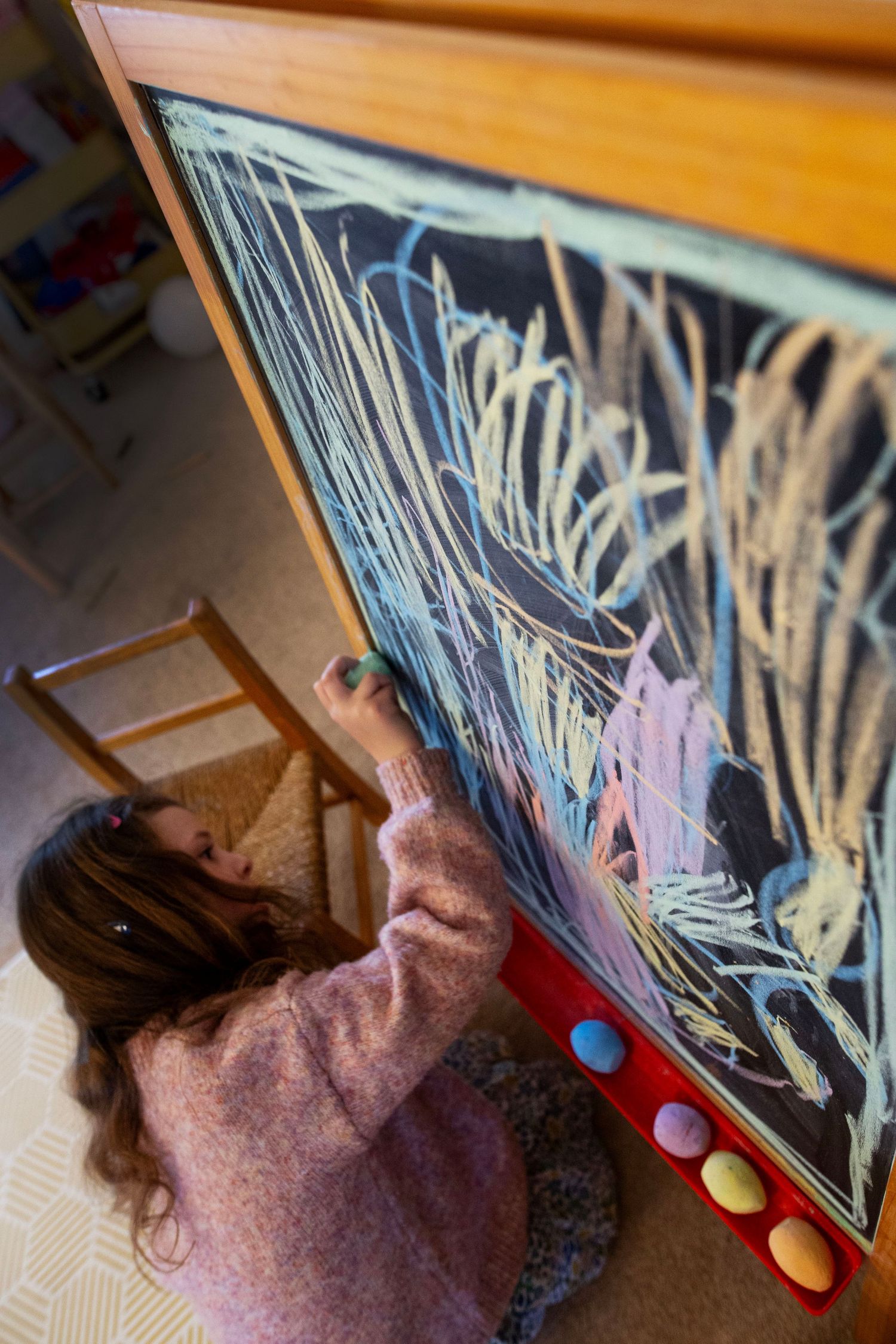 A girl draws on a blackboard. Candid and fun documentary family and childhood photoshoot by The Mother's Eye in Dulwich, South East London.