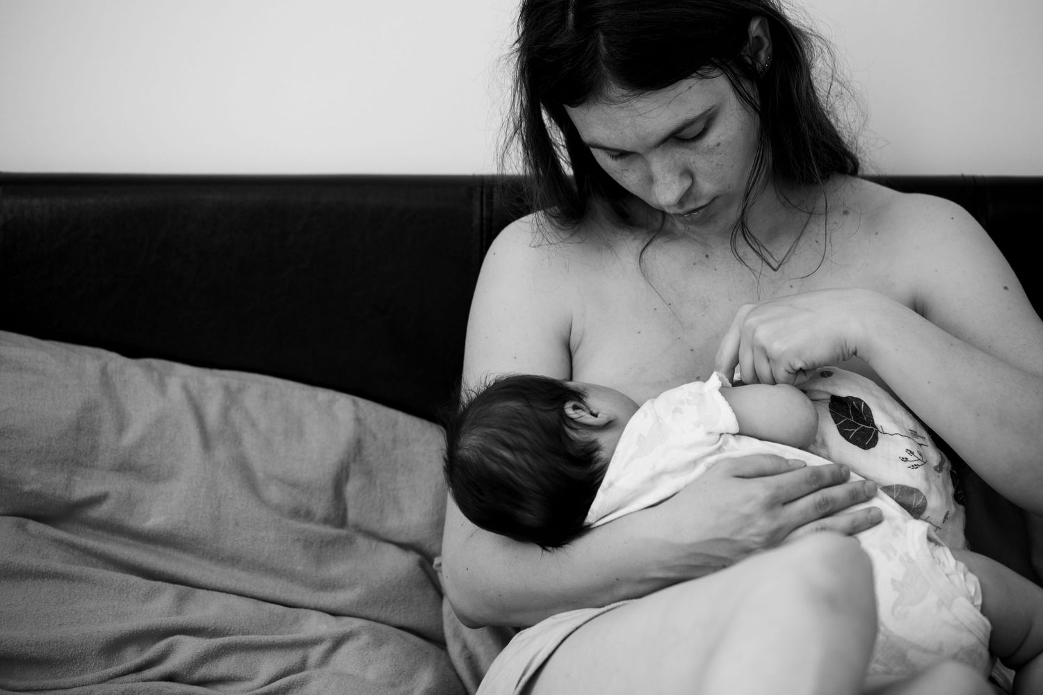 Self-portrait of The Mother's Eye photographer breastfeeding her baby on a bed in black and white. Family photography East Dulwich, London.