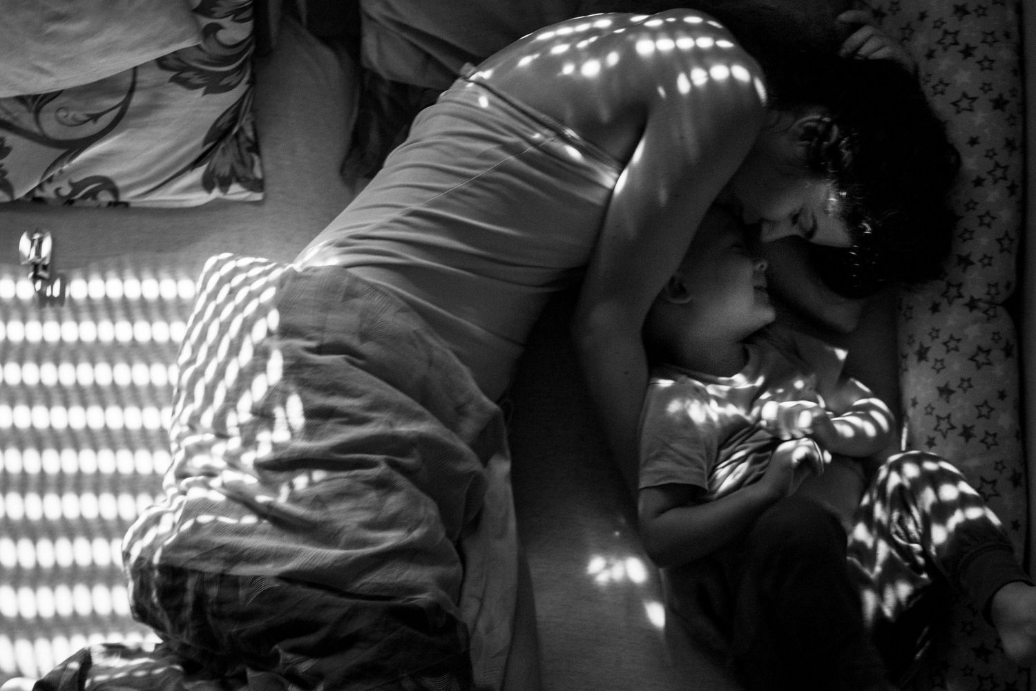 Mum and toddler in beautiful light on bed. Postpartum and motherhood photography by The Mother's Eye in Battersea, South East London.