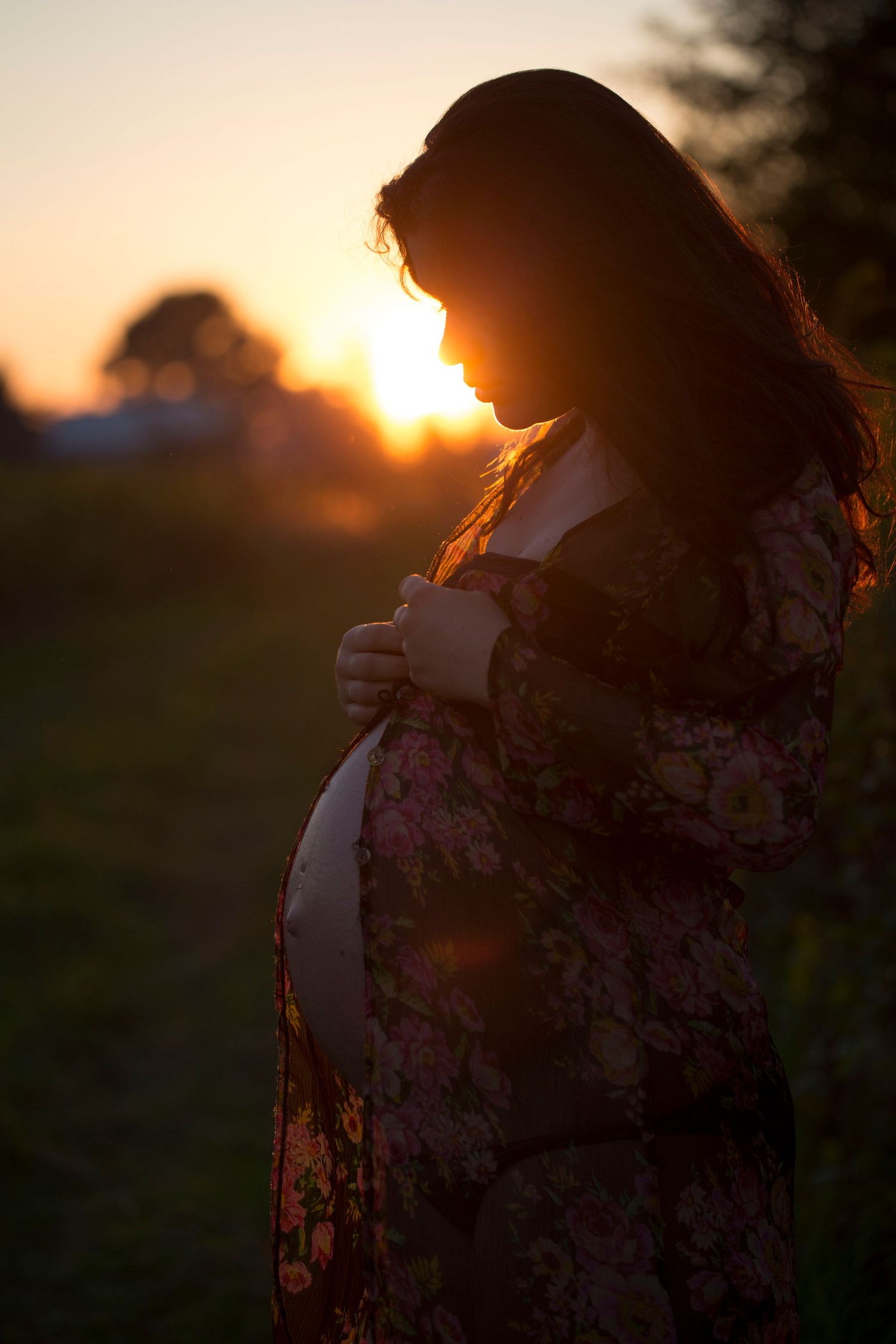 Pregnant woman in a field at sunset. Maternity and pregnancy photography by The Mother's Eye in Sydenham, South East London.