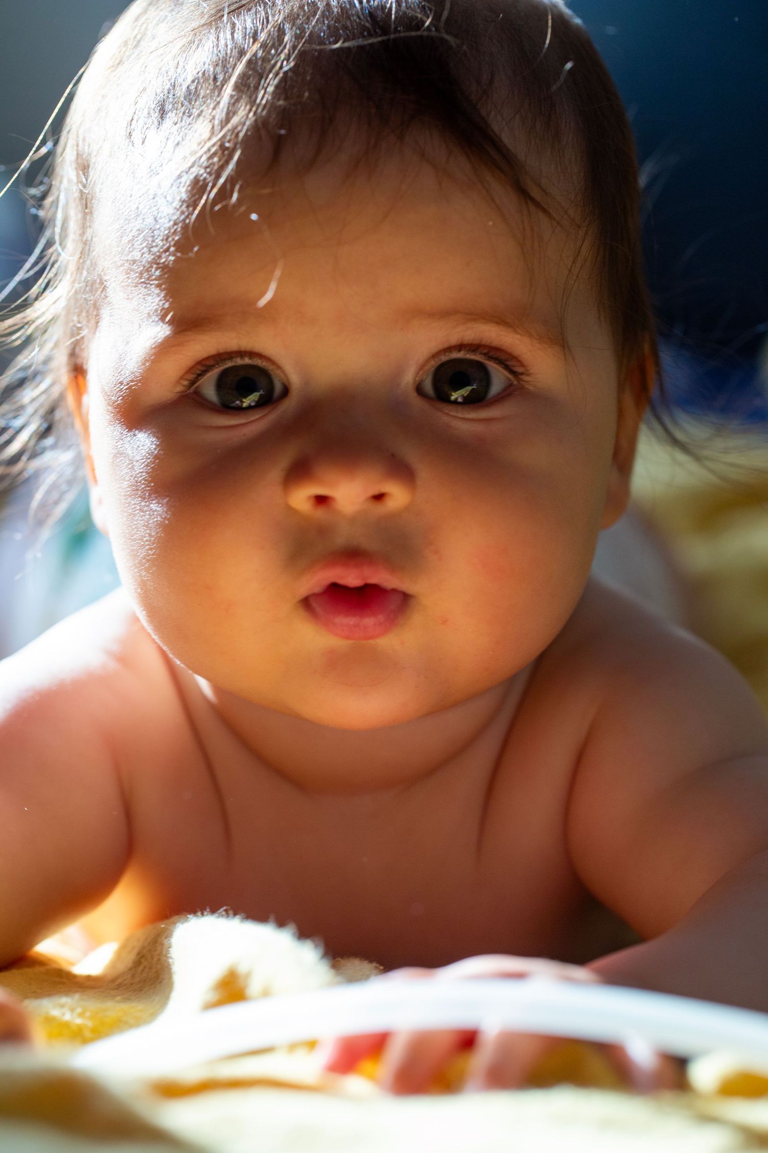 A baby laying on bed in a golden light. Childhood, newborn and family photography by The Mother's Eye, Beckenham, South East London.