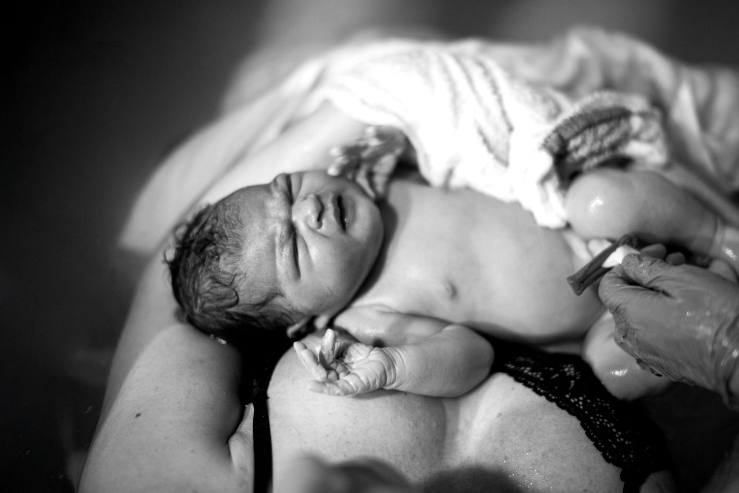 Newborn having her cord clamped. The Mother's Eye - candid documentary home birth photography in Denmark Hill, South East London.