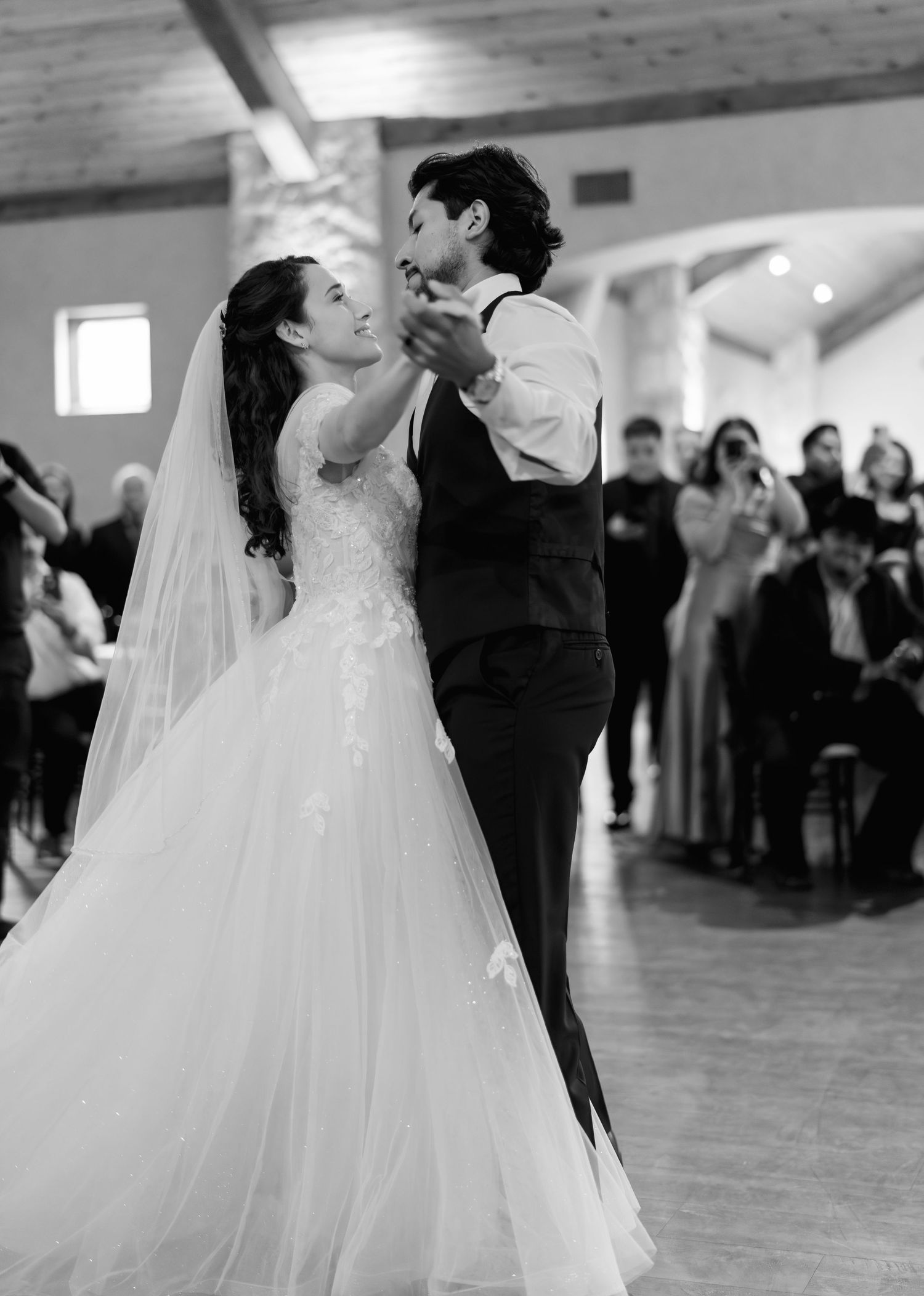 Black and white photo of bride and groom sharing their first dance at wedding reception.