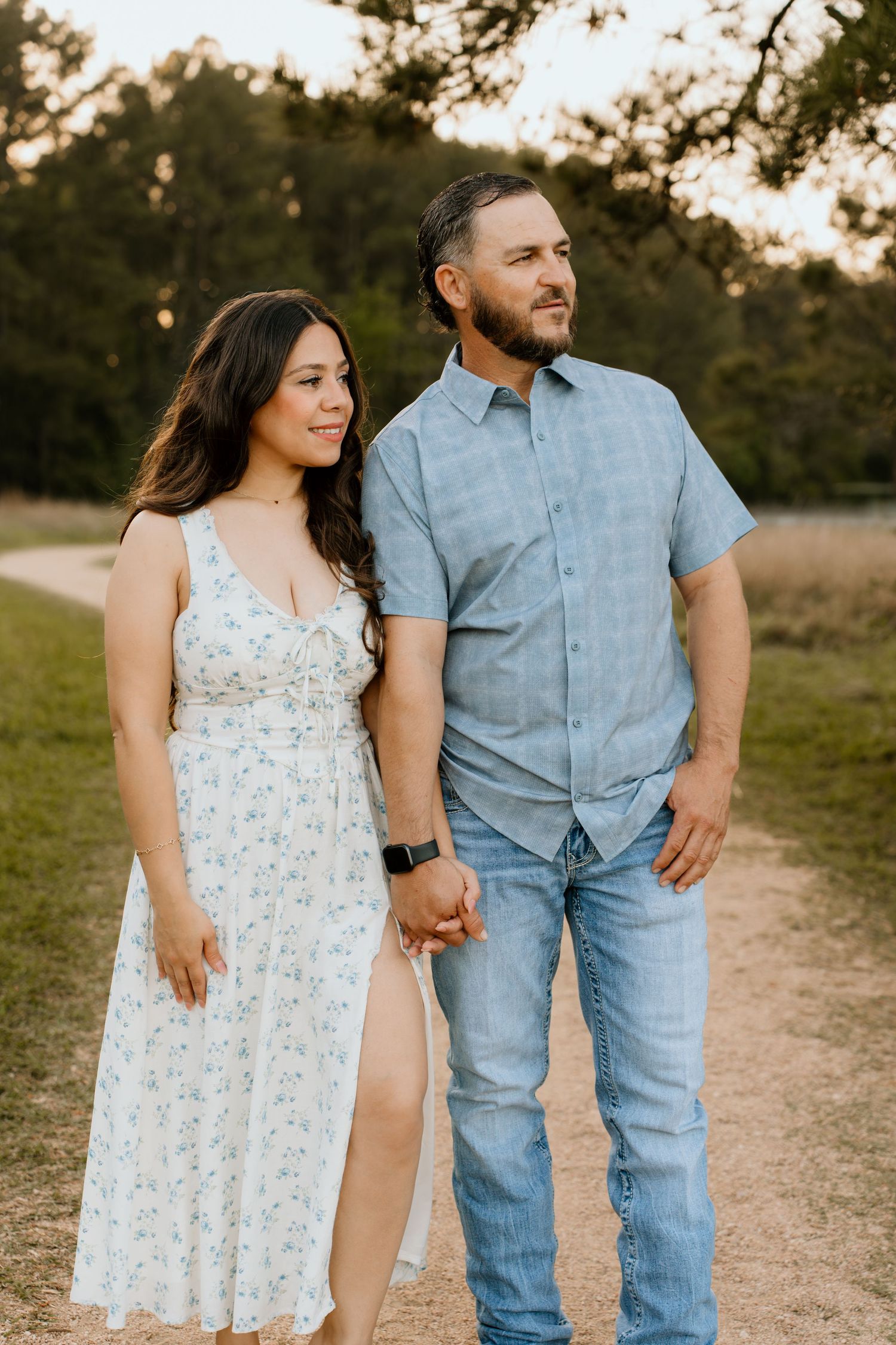 Couple walking hand in hand on outdoor path at sunset.