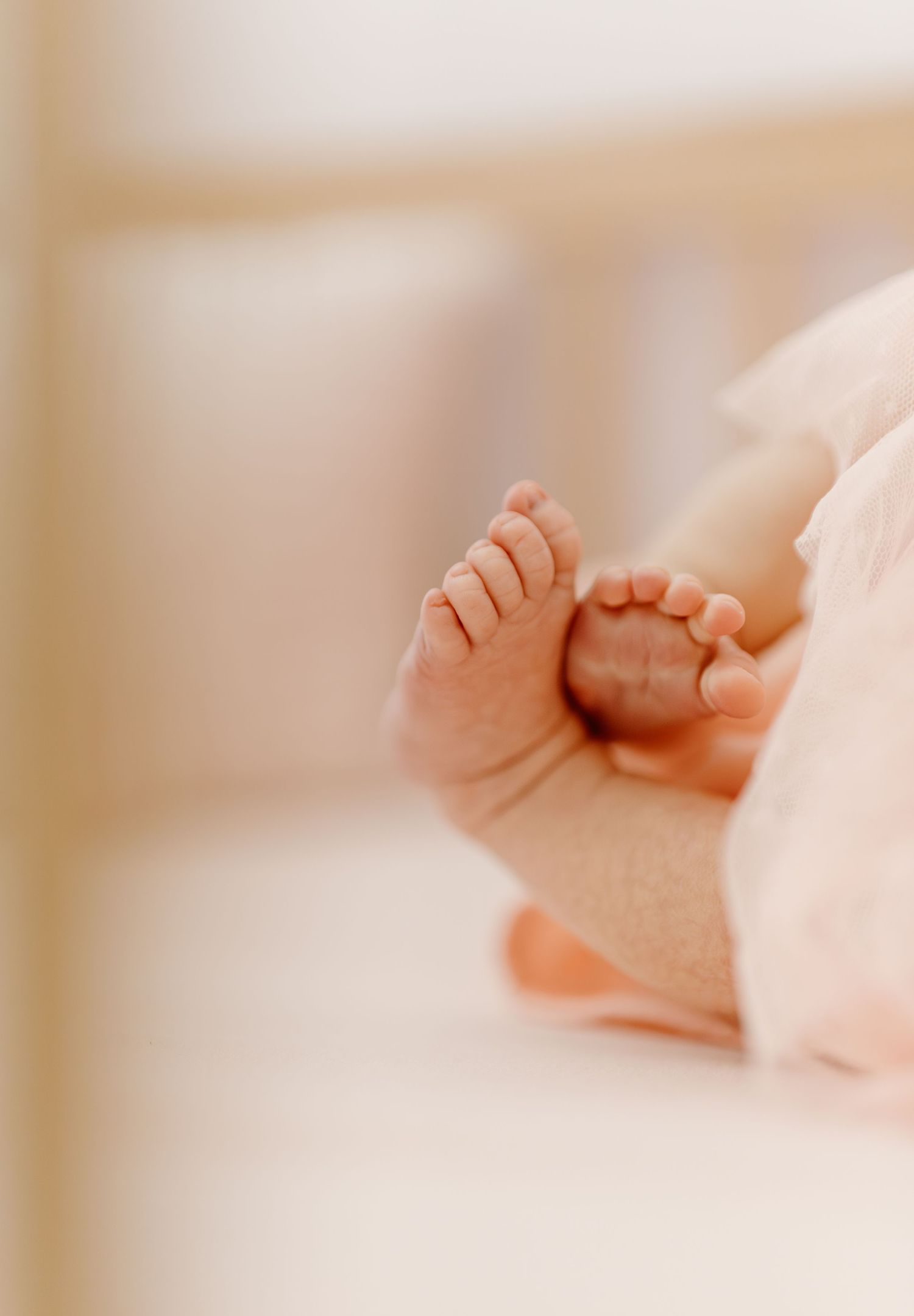 Close-up of tiny newborn baby feet and toes, soft pink background, delicate infant photography.