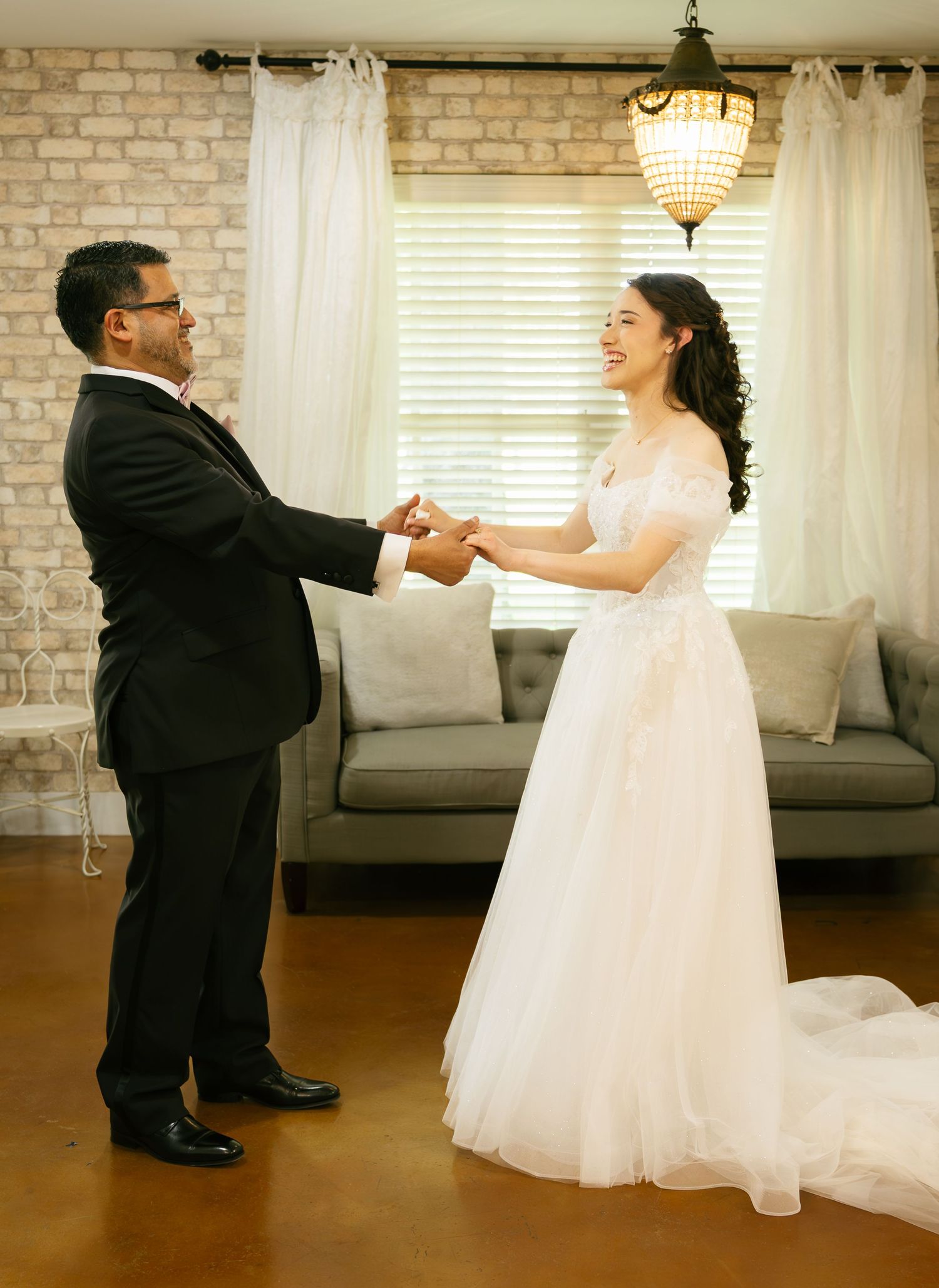 Bride and groom sharing a joyful first look dance in a sunlit rustic room.