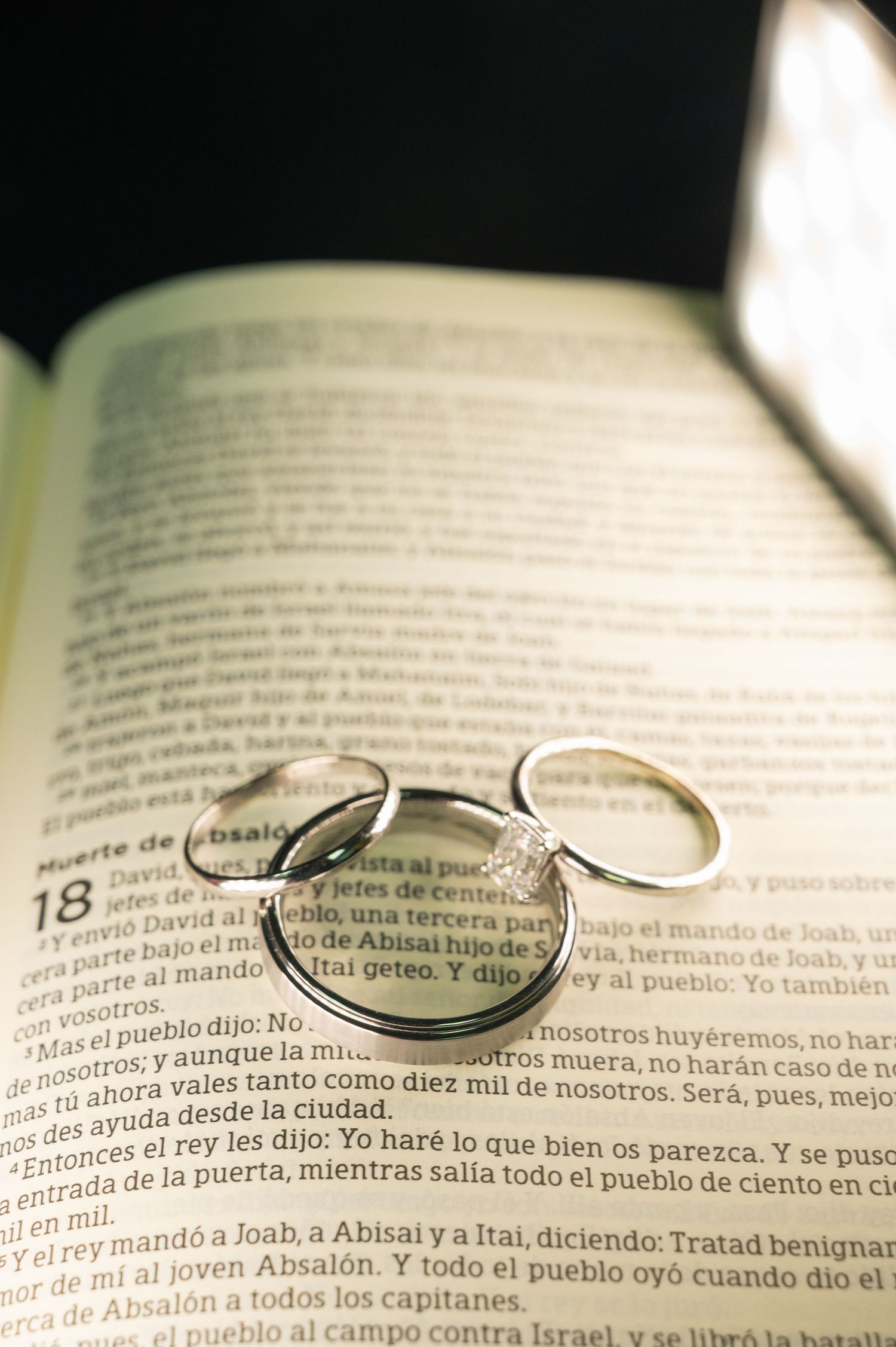 Wedding rings resting on open Spanish Bible page symbolizing faith and marriage commitment.
