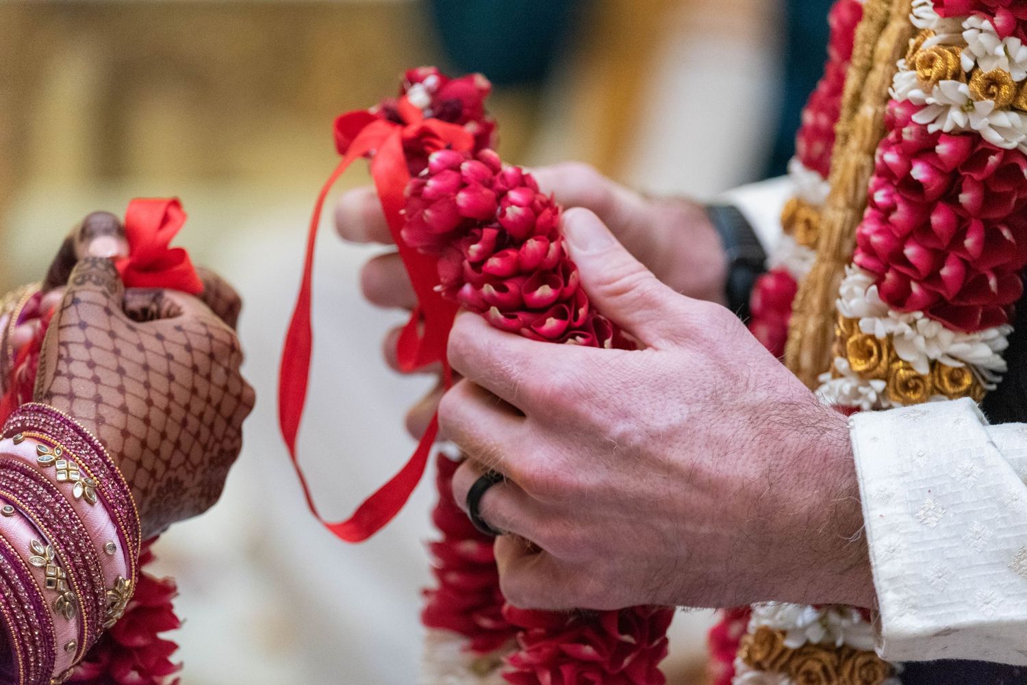 Bride and groom exchanging red floral garlands during traditional Indian wedding ceremony.