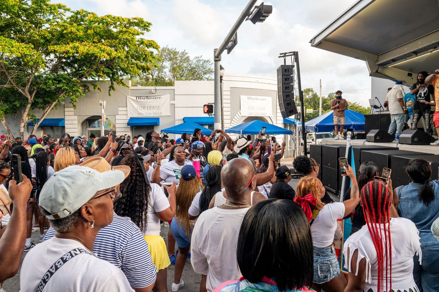 Outdoor concert crowd enjoying live music performance on sunny day at urban festival stage.