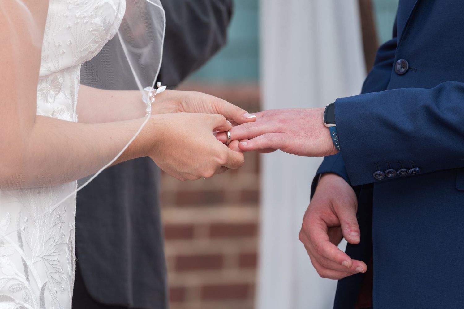 Close-up of bride placing a wedding ring on the grooms finger during the ceremony.