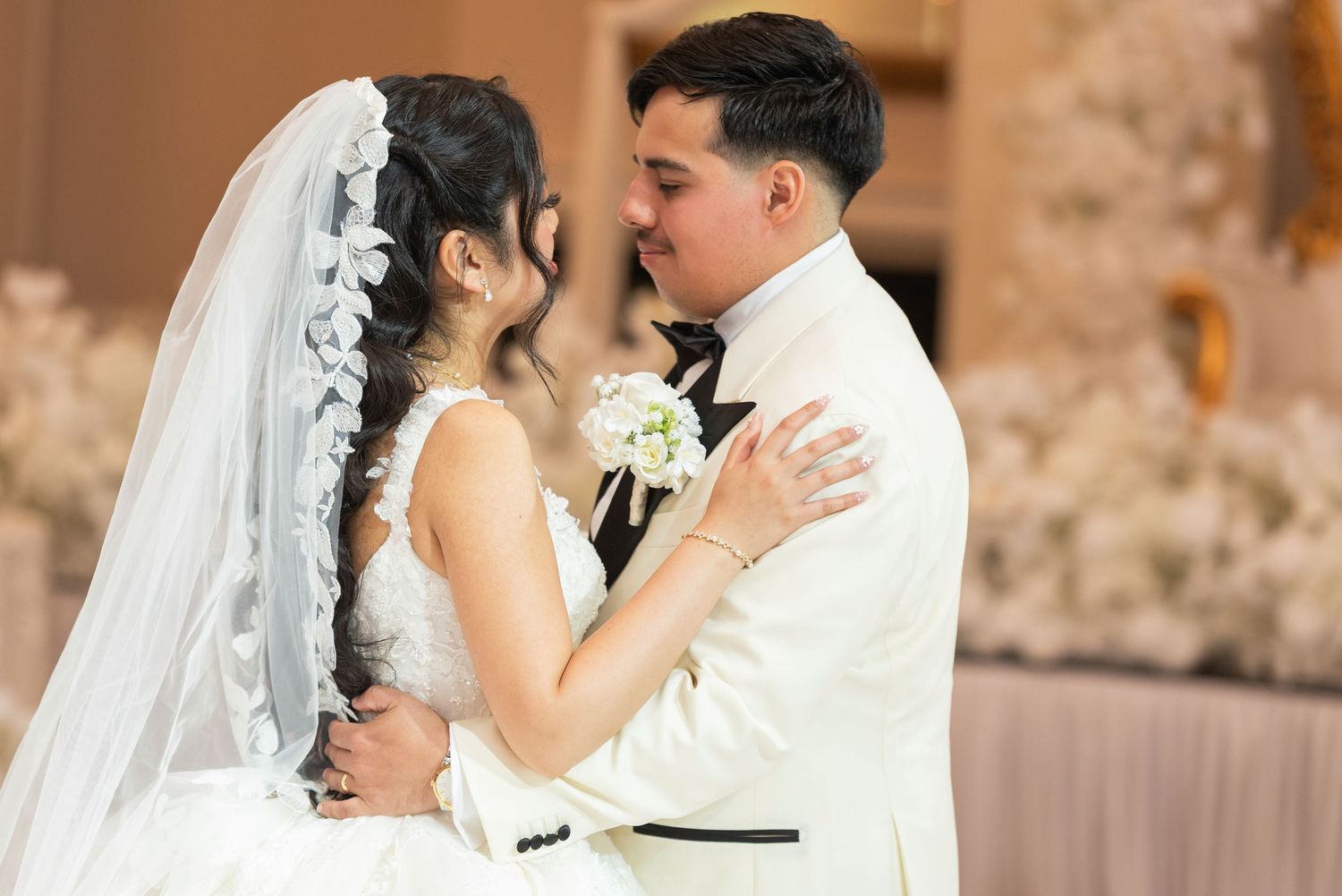 Bride and groom share a romantic first dance at elegant wedding reception with white floral decor.