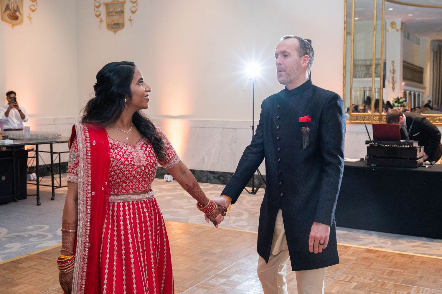 Couple shares first dance in elegant Indian fusion attire at traditional wedding reception celebration.