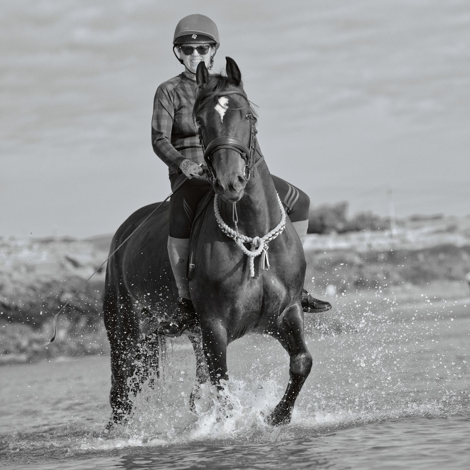 Horse splashing through waves on the beach, rider happy during an equine photography shoot. Aberffraw, North Wales, DM for a shoot.