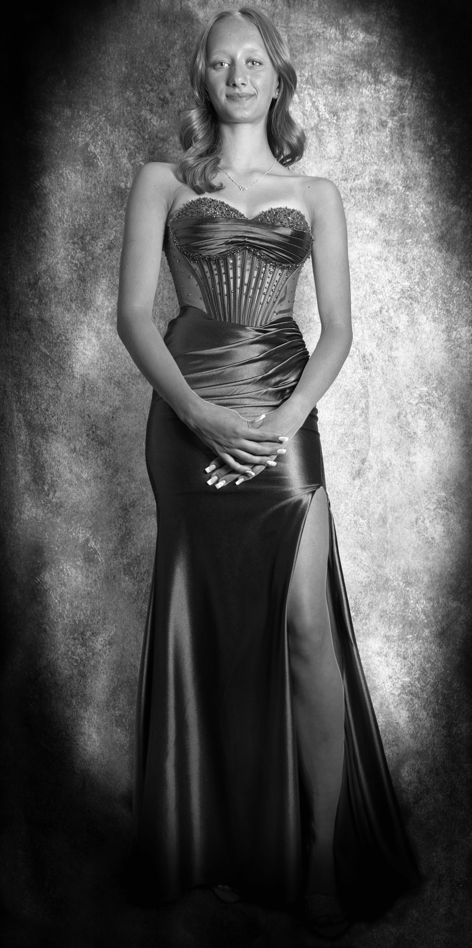 Young woman in an elegant prom dress posing for a studio photo session with professional lighting and portrait photography setup