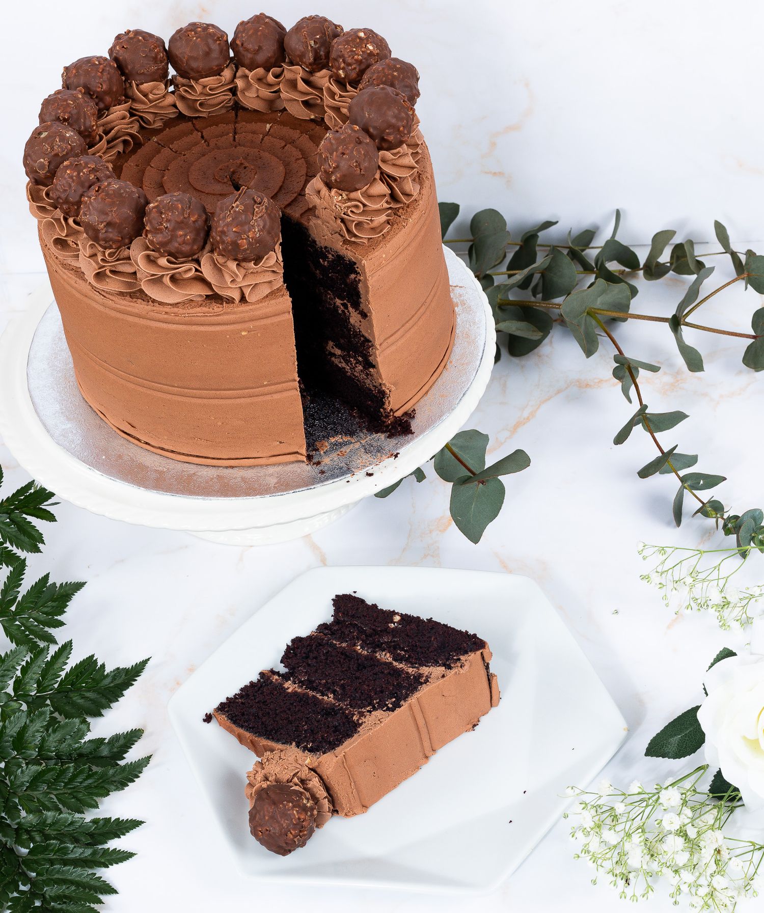 Decadent chocolate layer cake with truffle toppings and a slice served on a white plate.