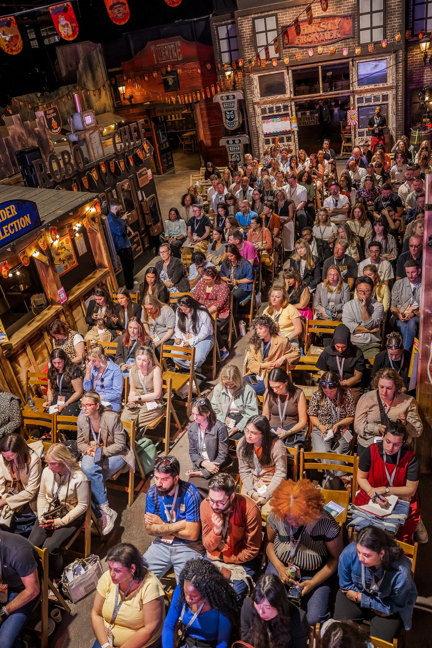 Aerial view of a large audience seated in chairs at an indoor conference in a themed venue.