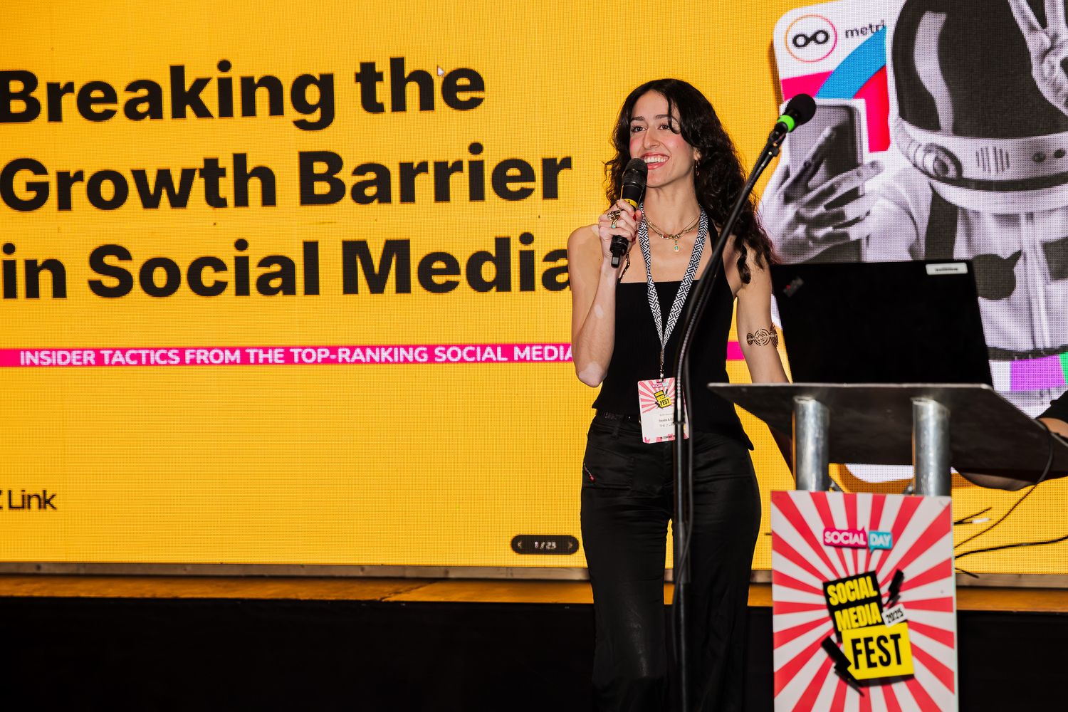 A woman speaks on stage at a social media conference presenting Breaking the Growth Barrier in Social Media.