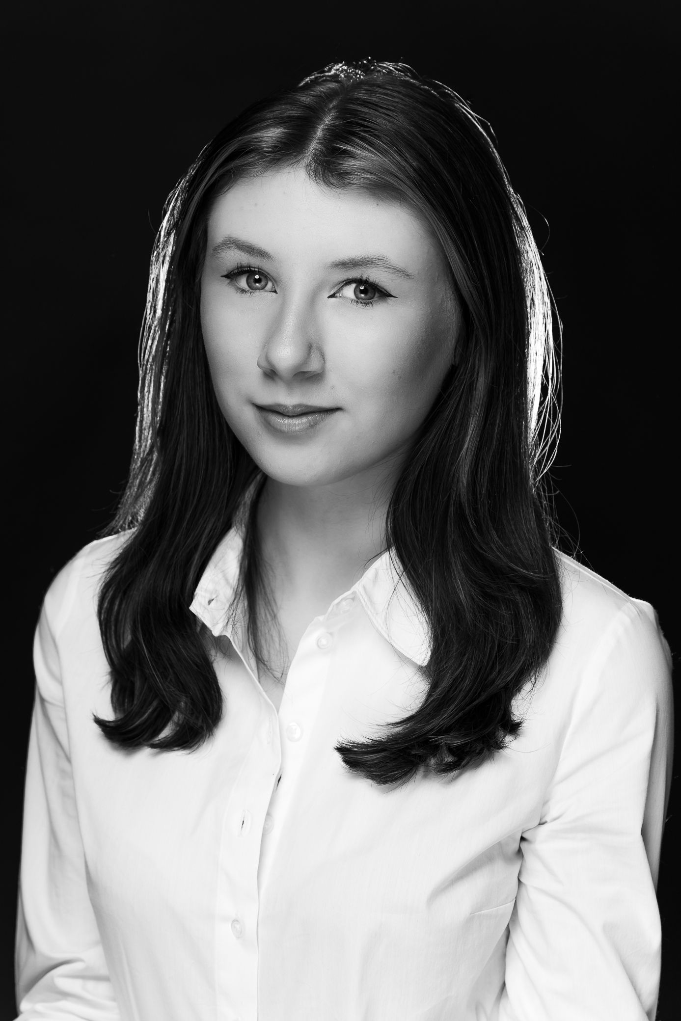 Black and white portrait of a young woman with long dark hair wearing a white button-up shirt.