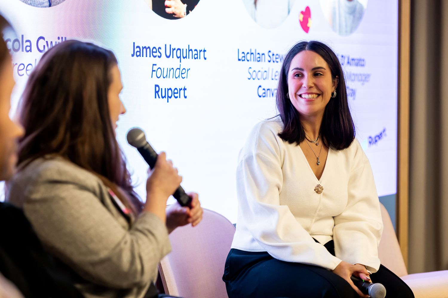 Two women engage in a panel discussion on stage at a professional conference event.