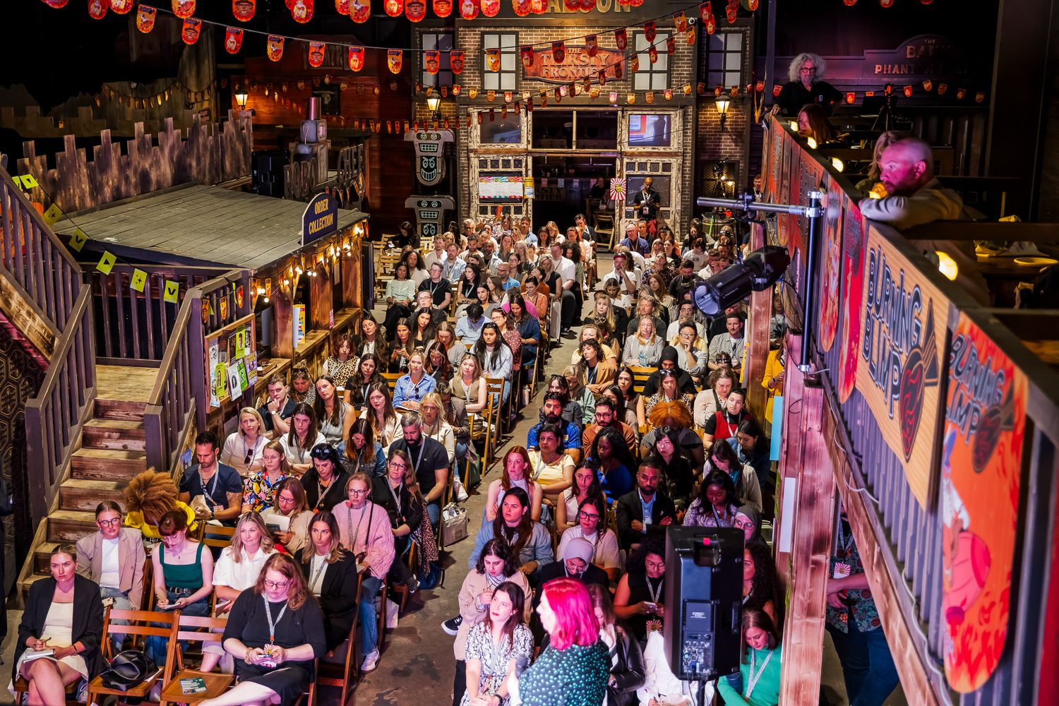 Bird's eye view of a large diverse crowd gathered at an indoor event in a themed entertainment venue.