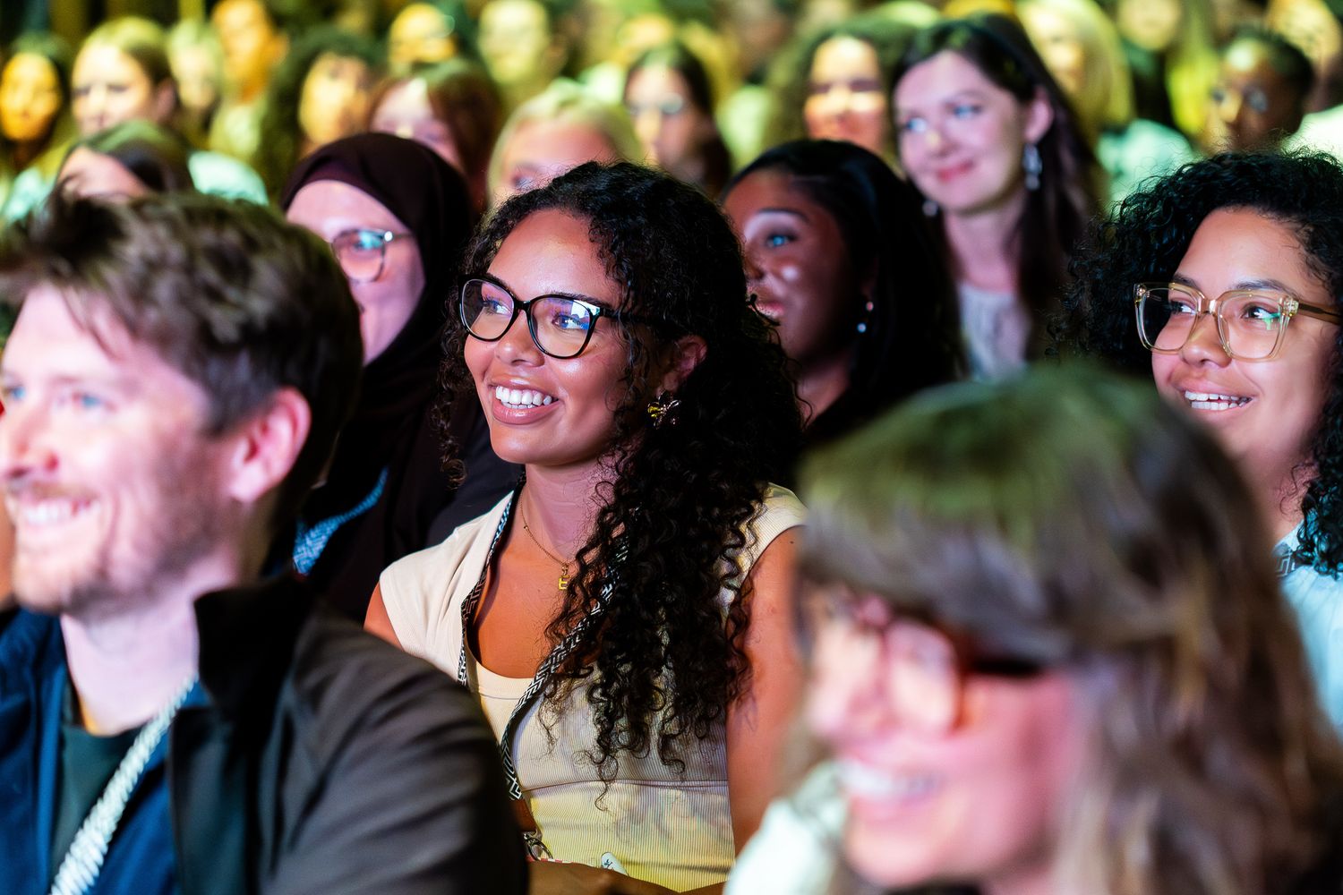 Diverse audience smiling and engaged during an inspiring conference or business event.