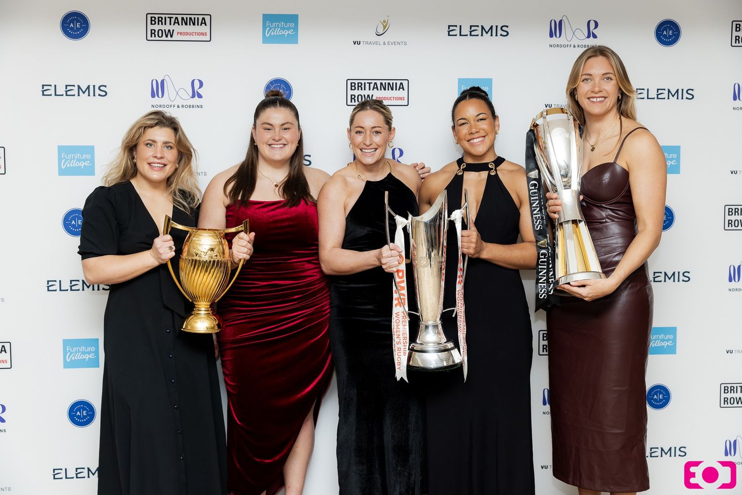 Five women in formal gowns pose with trophies at a Britannia Row Awards ceremony with Elemis branding.