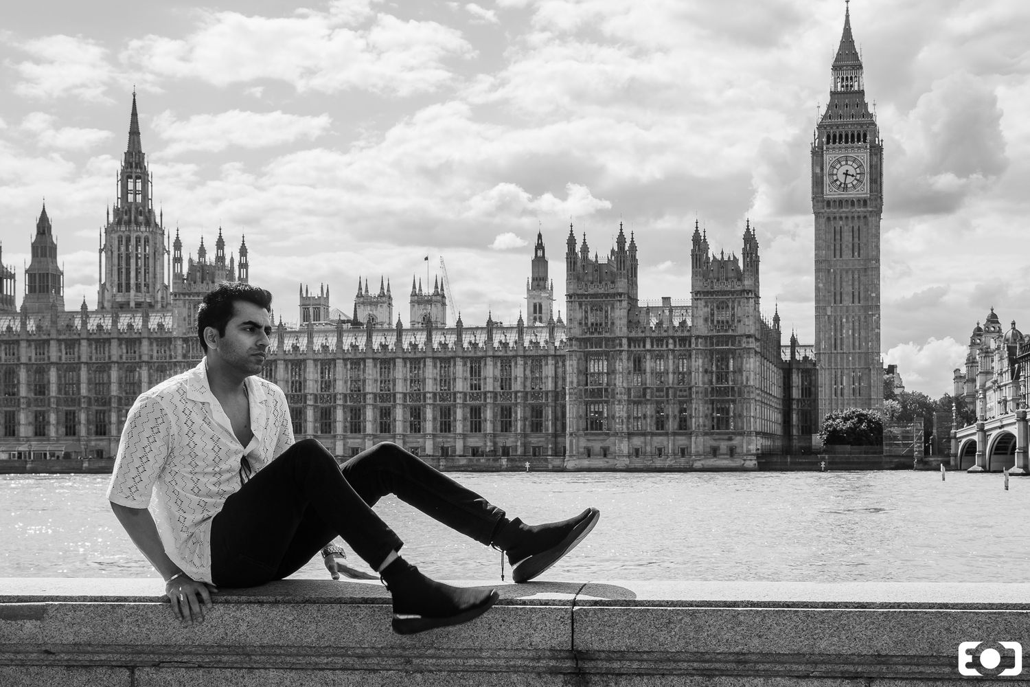 Man sitting on a wall with Big Ben and Houses of Parliament in background, black and white London photography.