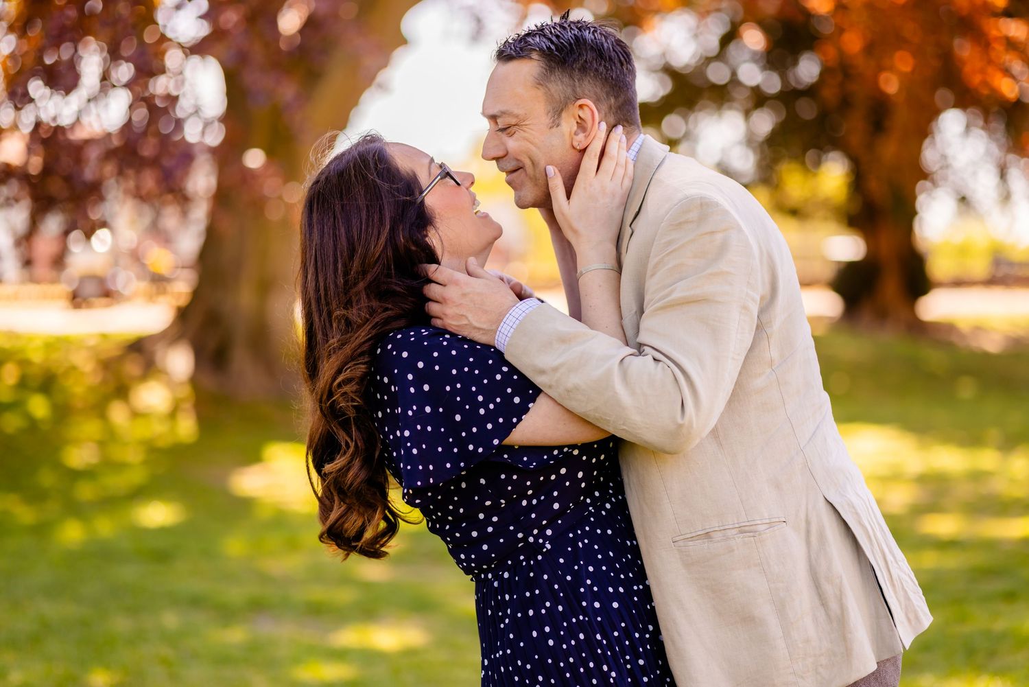 Couple sharing a romantic moment embracing and smiling in a sunny autumn park setting.