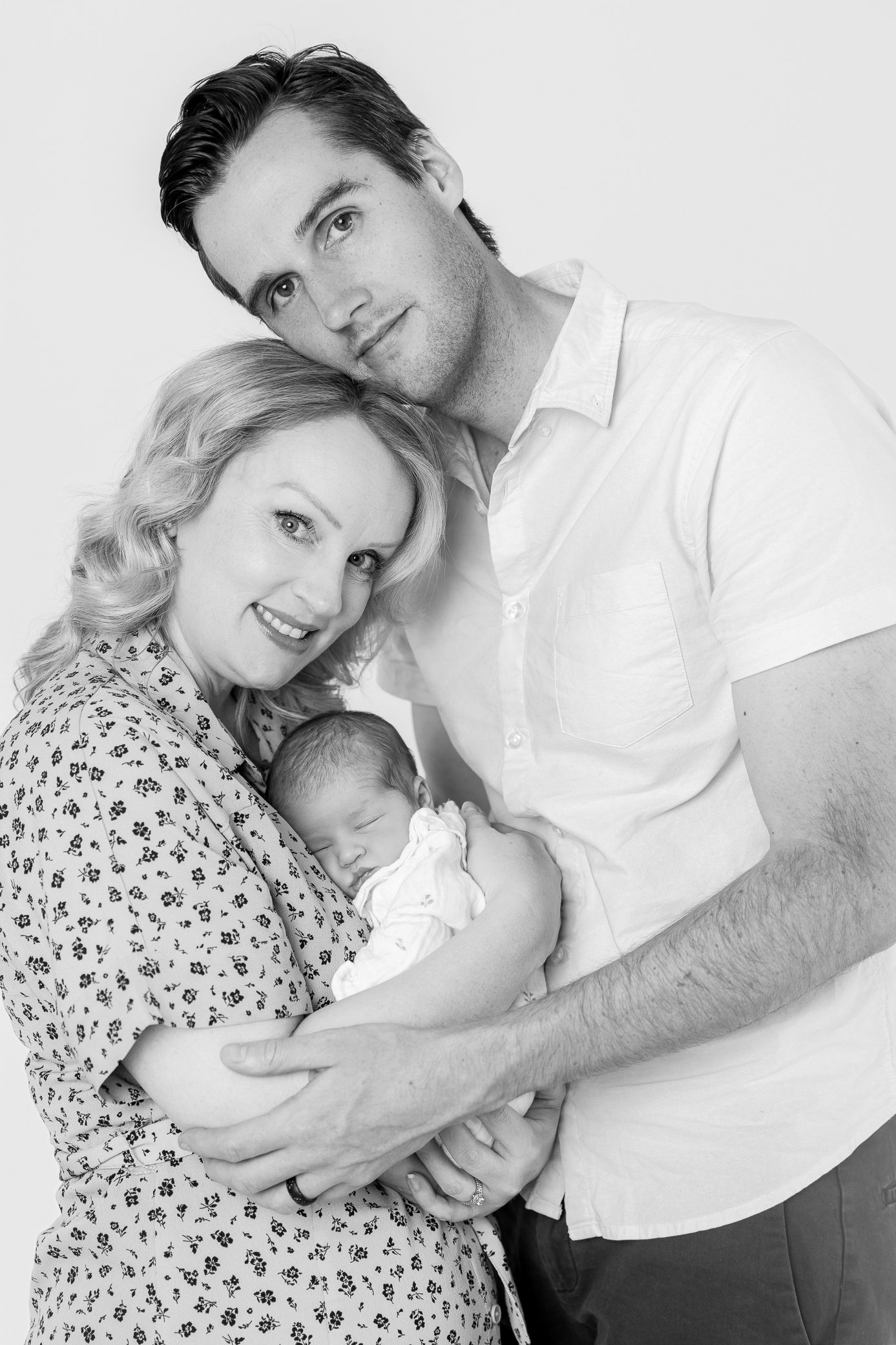 Black and white portrait of parents holding their sleeping newborn baby.