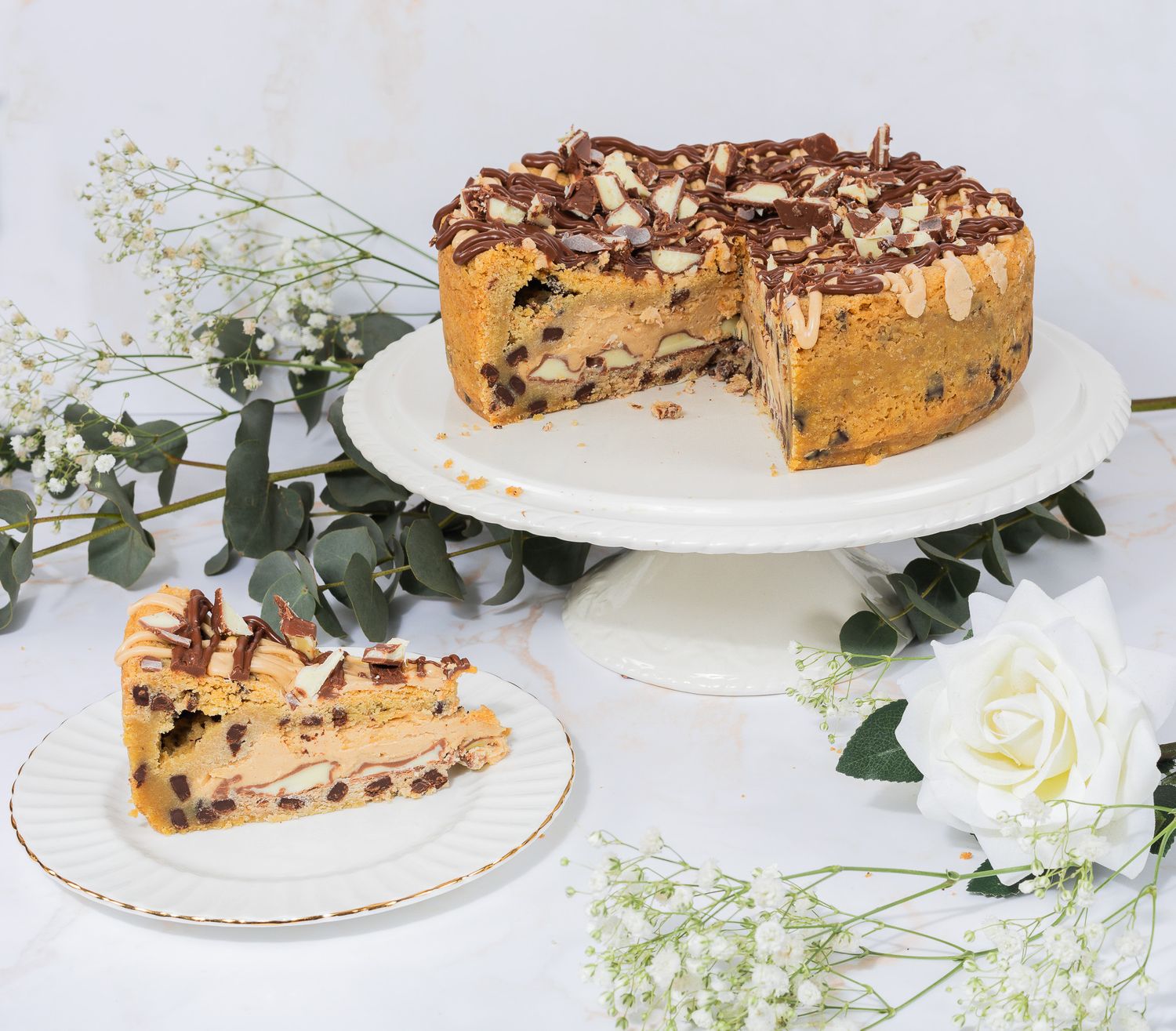 Delicious chocolate chip cheesecake with caramel drizzle and a slice on a white cake stand.