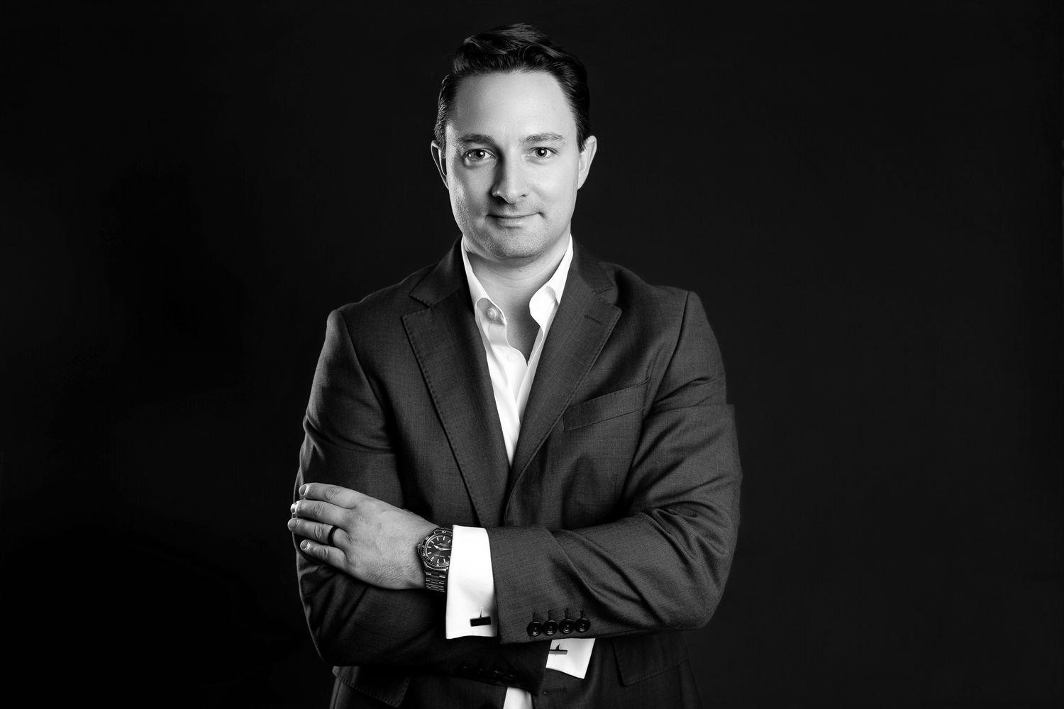 Professional black and white portrait of a businessman in a suit with arms crossed.