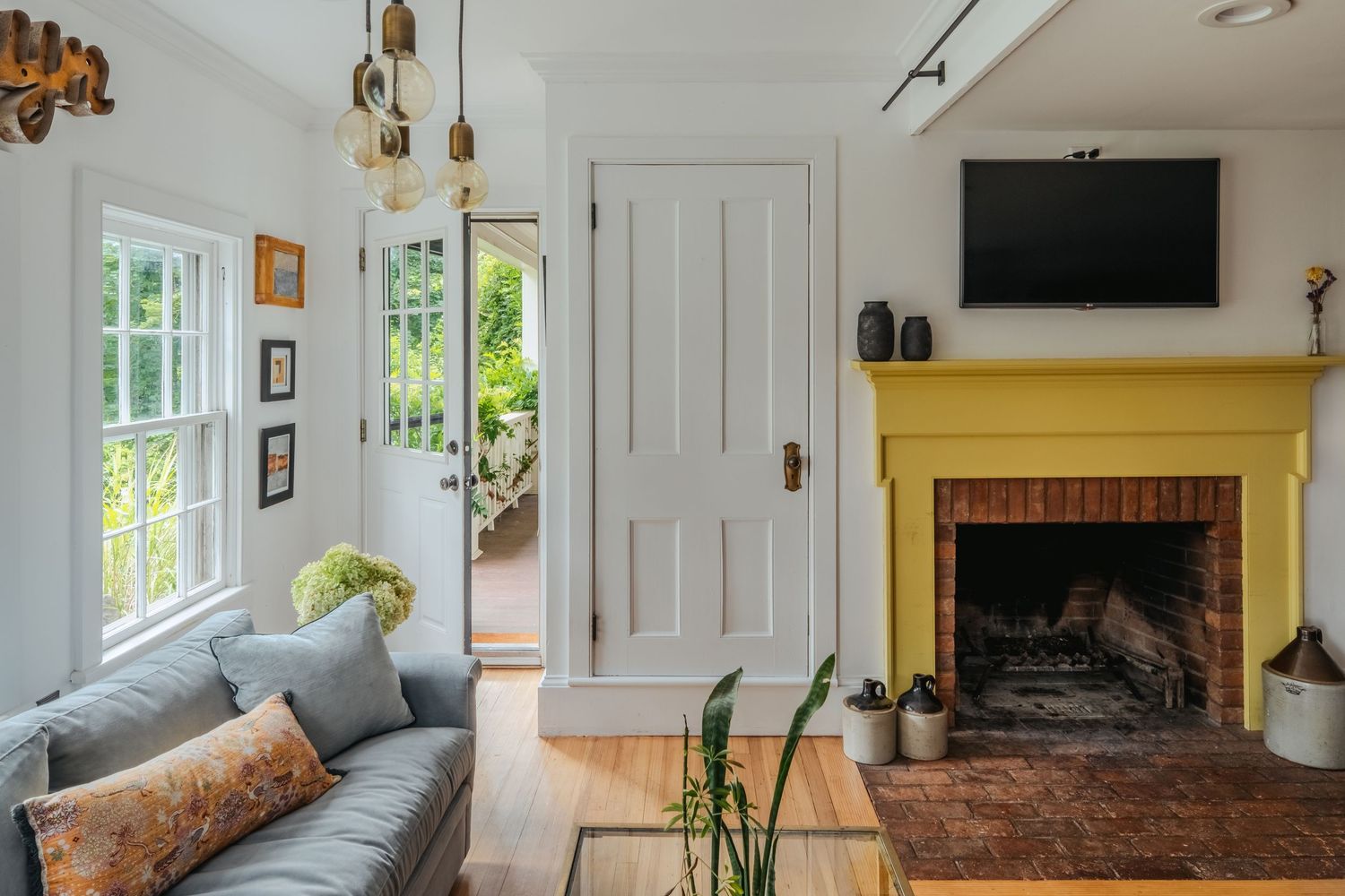 A bright and airy living room features white walls, hardwood floors, and a cozy fireplace with modern furnishings.