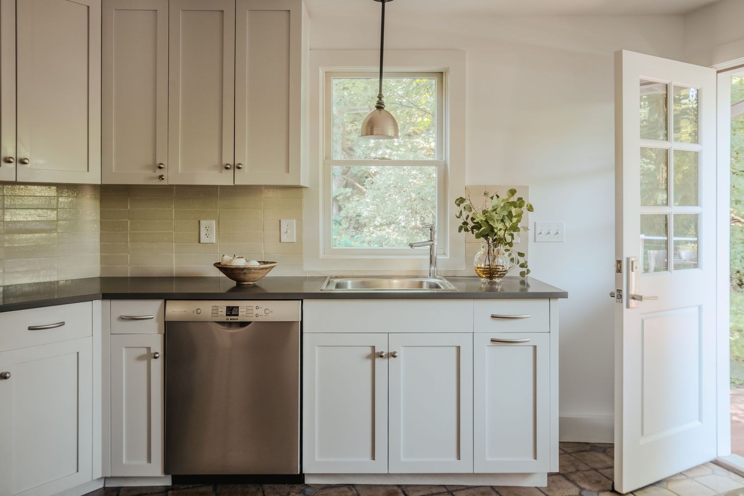 White contemporary kitchen with shaker cabinets, stainless steel appliances, and quartz countertops in an open layout.