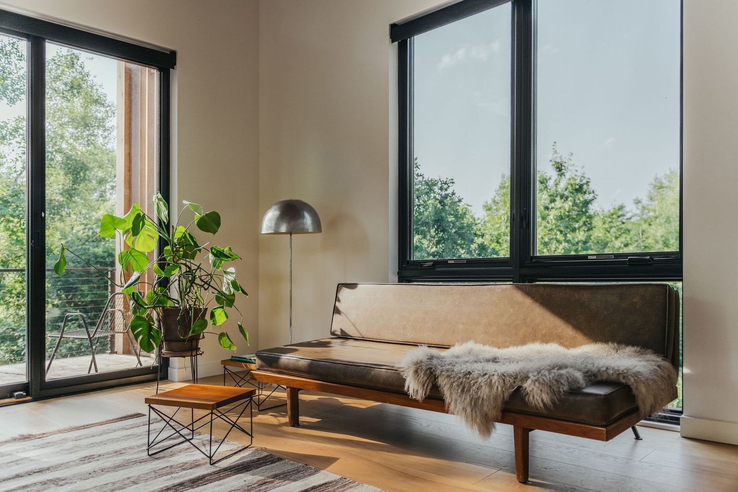 Modern living space with daybed, floor lamp, and large windows offering natural light.