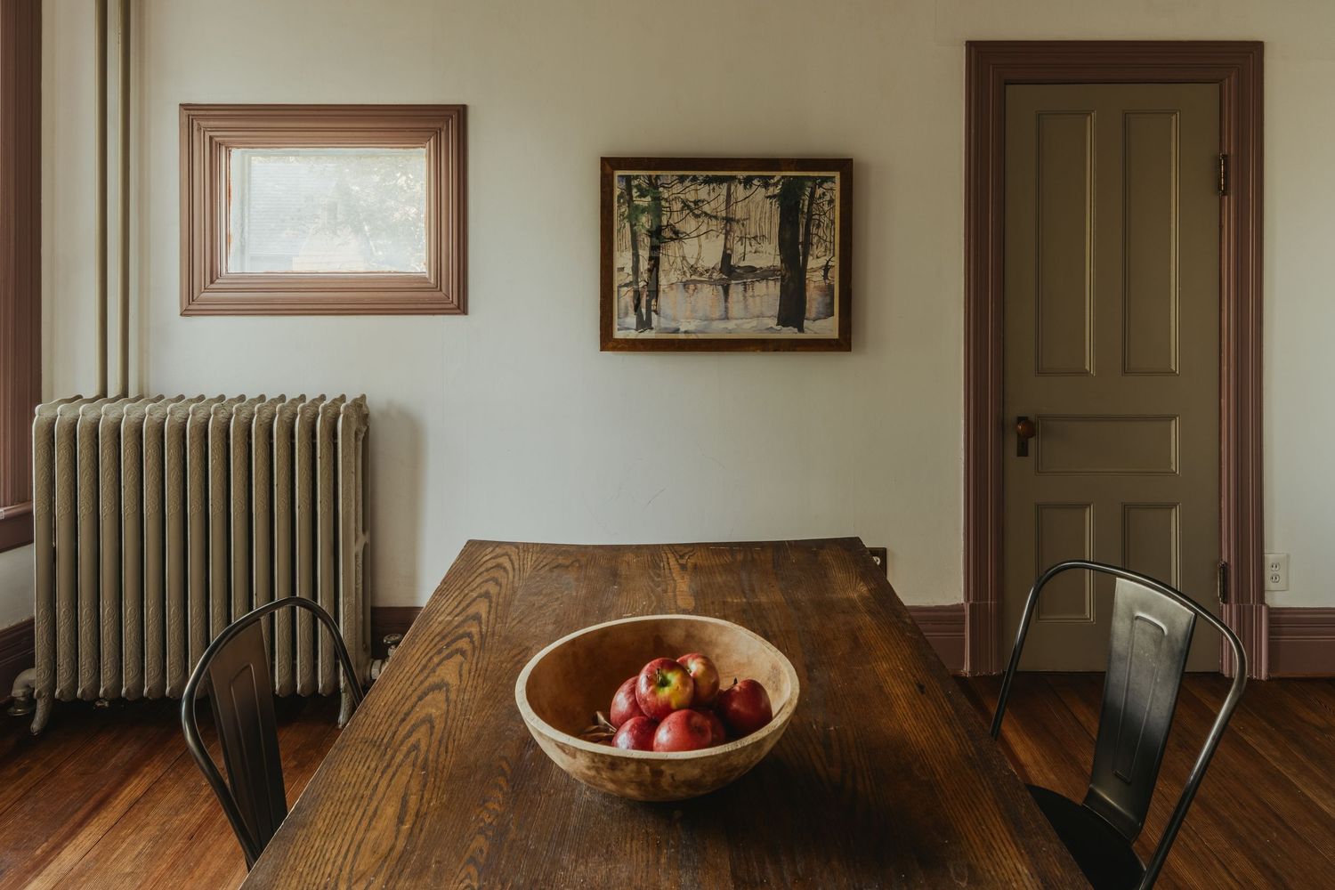 A series of vintage radiators and doorways in a historic home interior hallway.