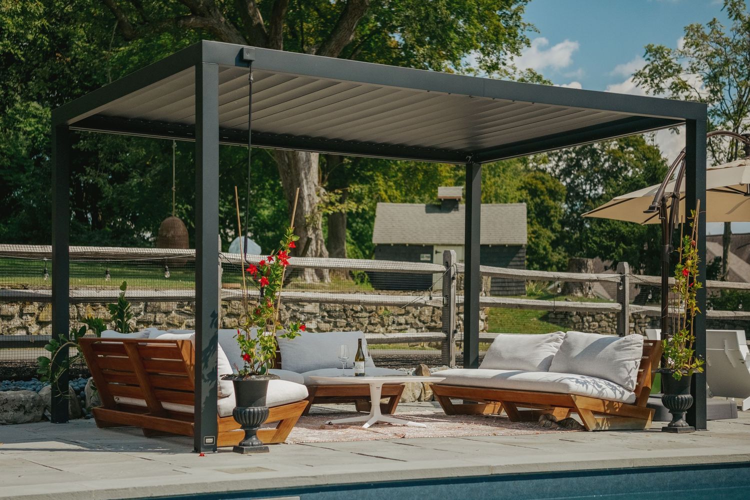 Modern outdoor patio area with sleek pergola, wooden furniture, and lush greenery creating a luxurious relaxation space.