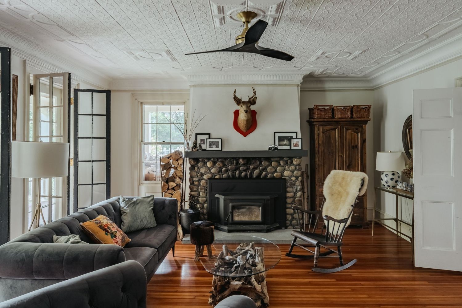 Panoramic view of a modern rustic living room with white walls, hardwood floors, and comfortable gray seating arrangements.